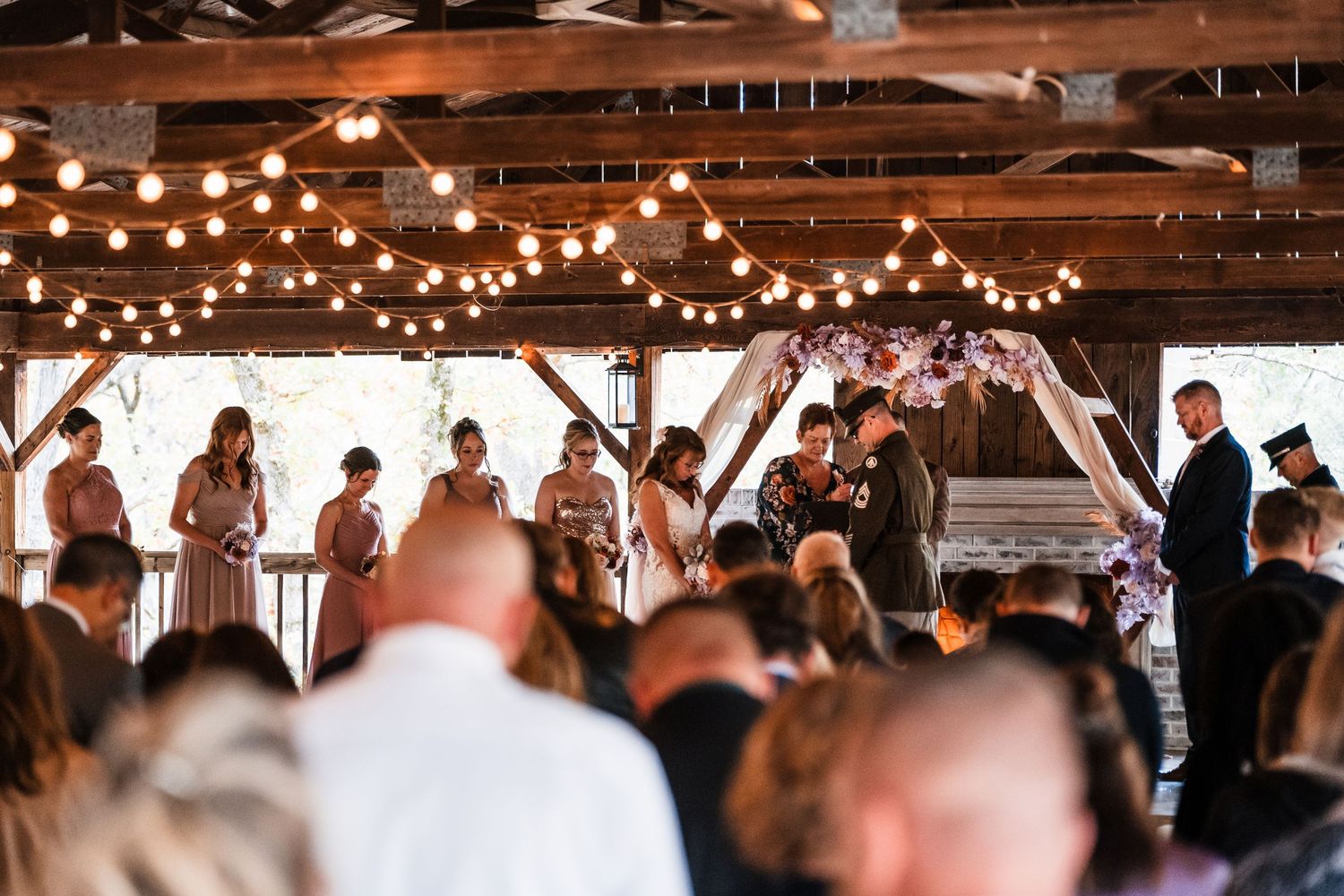 Wedding reception venue decorated with warm string lights and wooden beams creating an intimate atmosphere.