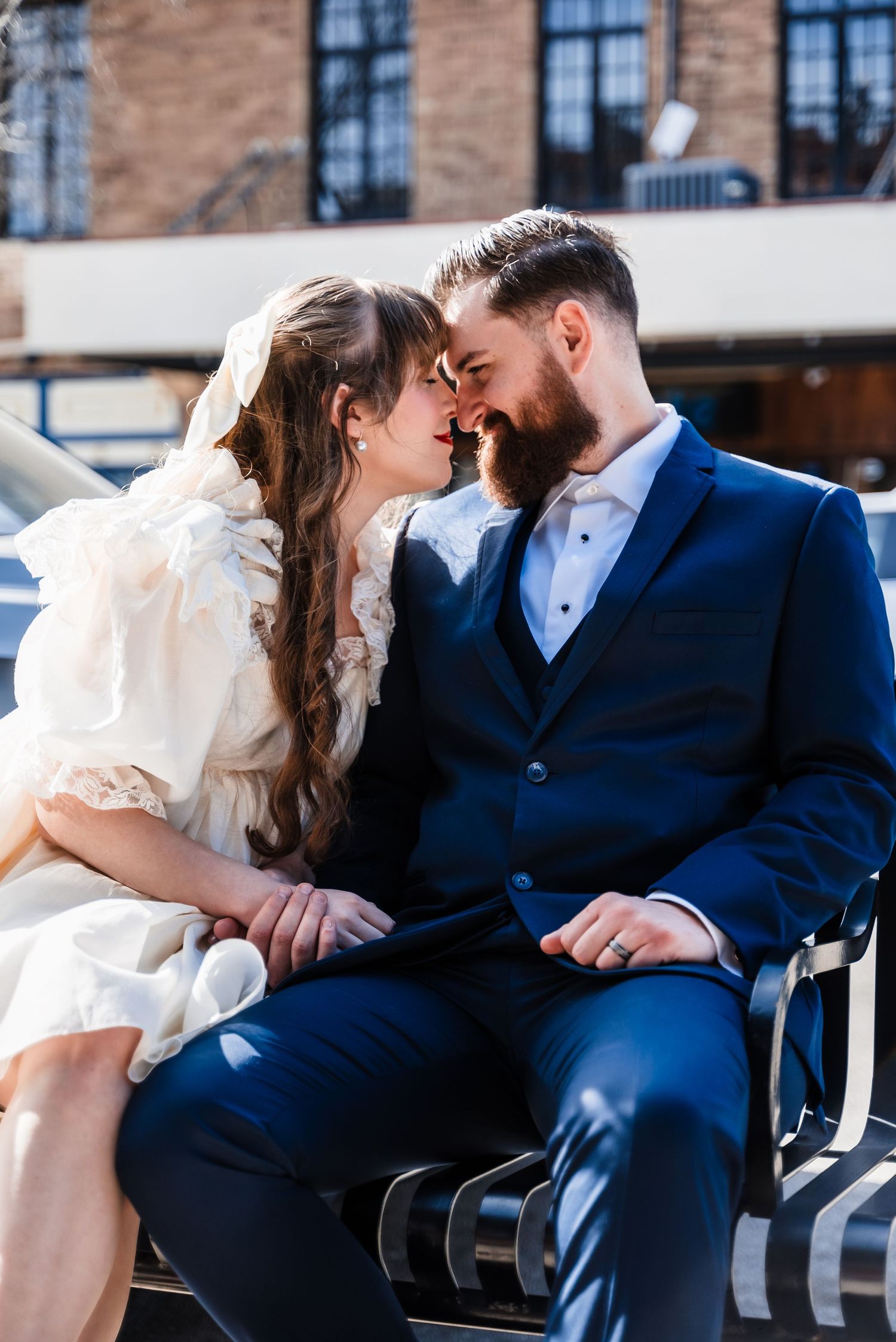 Intimate moment between couple on bench in casual outdoor wedding setting.
