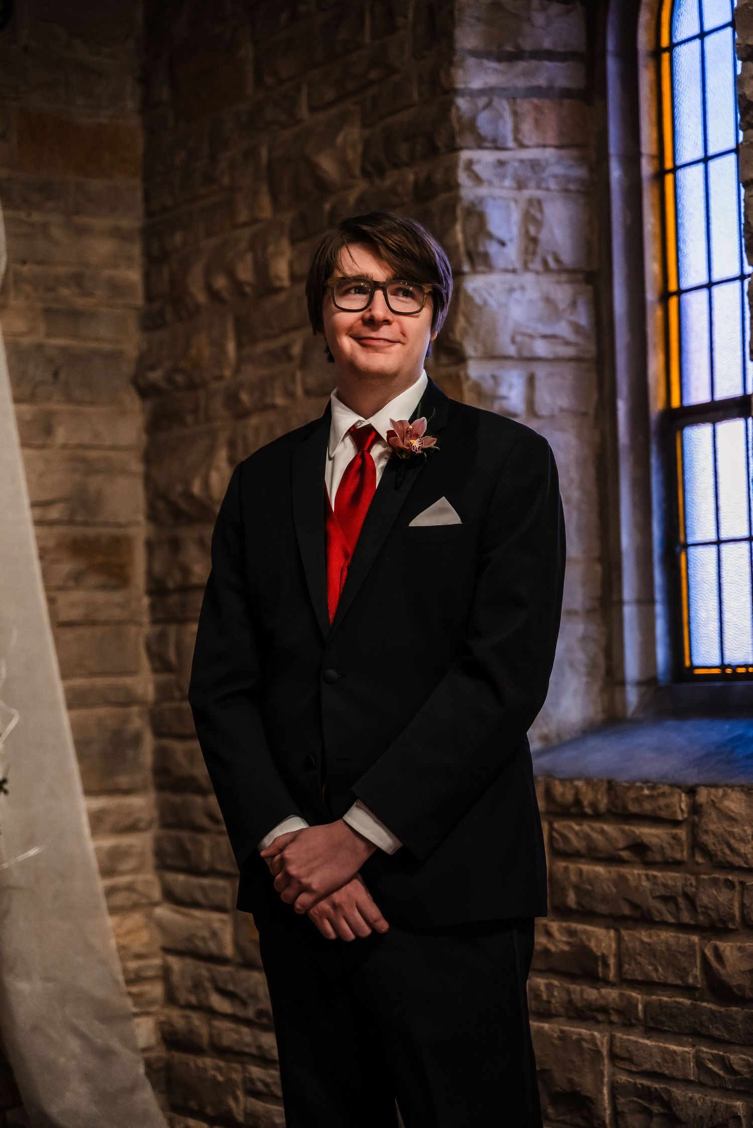 Formal portrait in a stone church with stained glass windows and natural lighting.