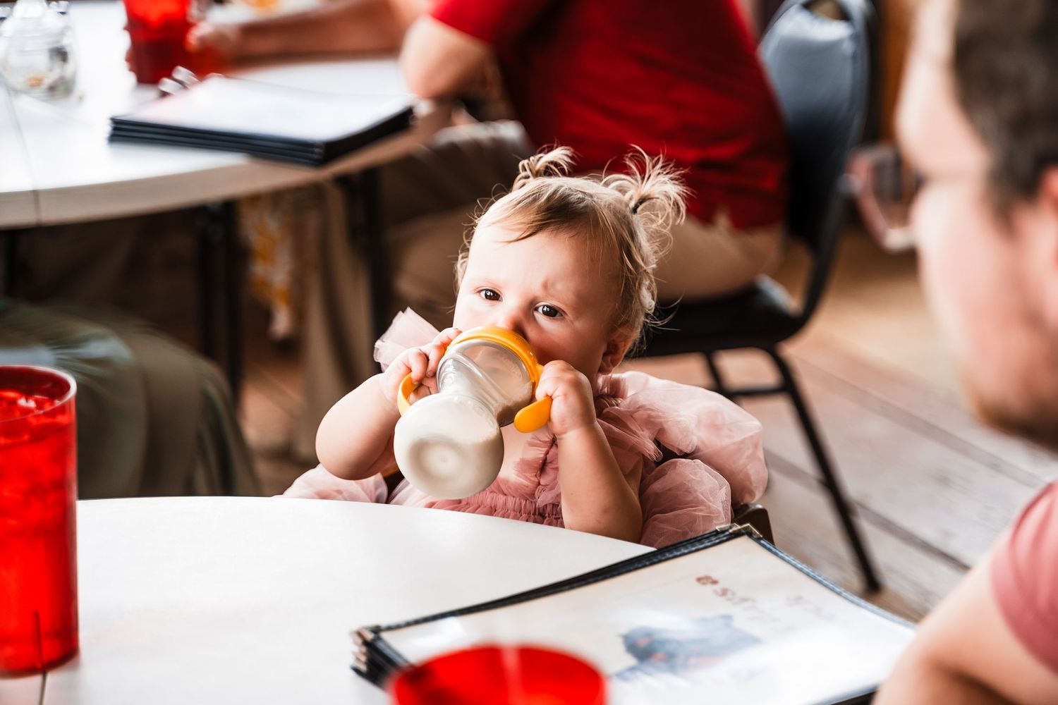 Small baby eating while seated at restaurant table with red cups visible.