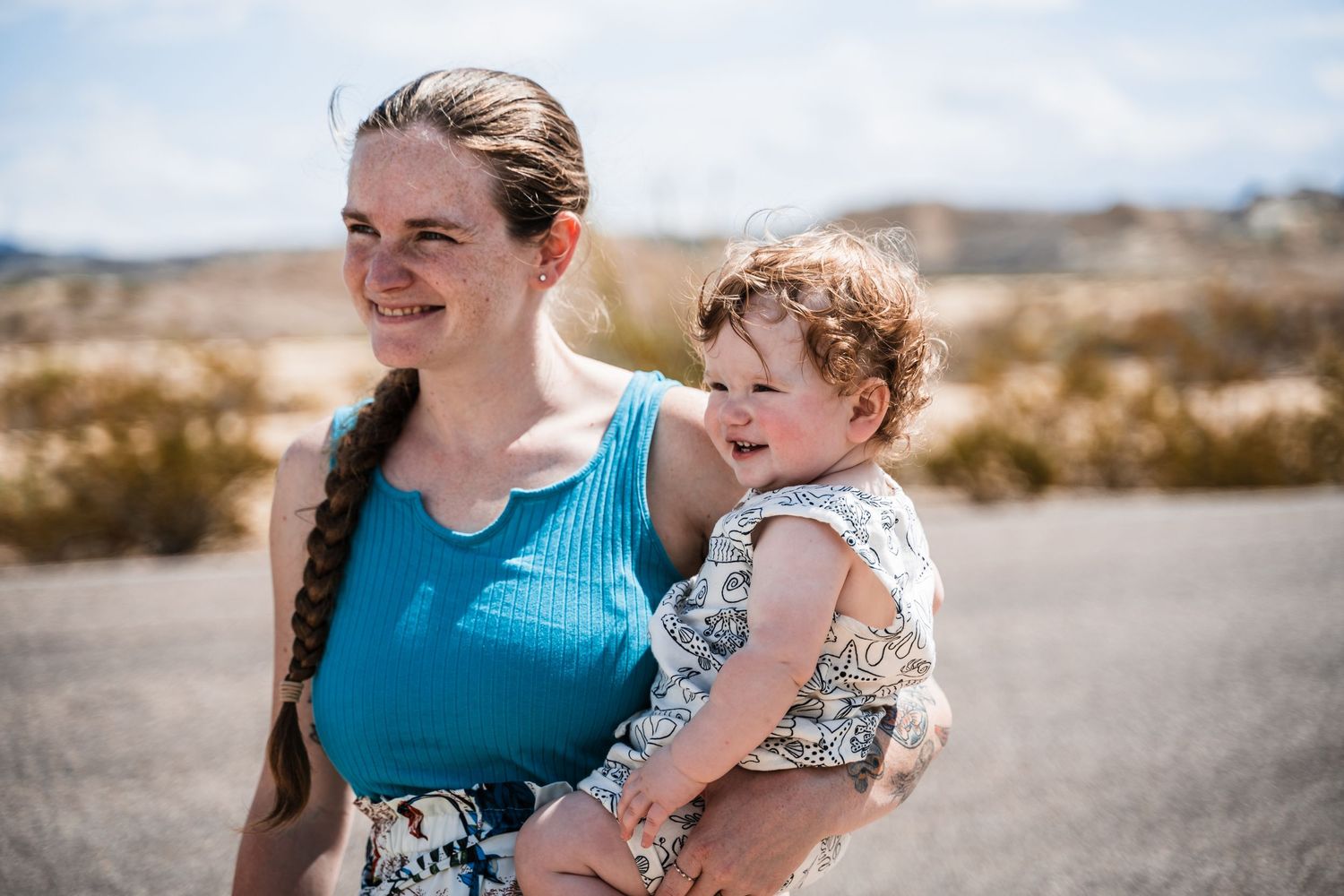 Parent and toddler enjoying a sunny day together on a desert path in warm weather.