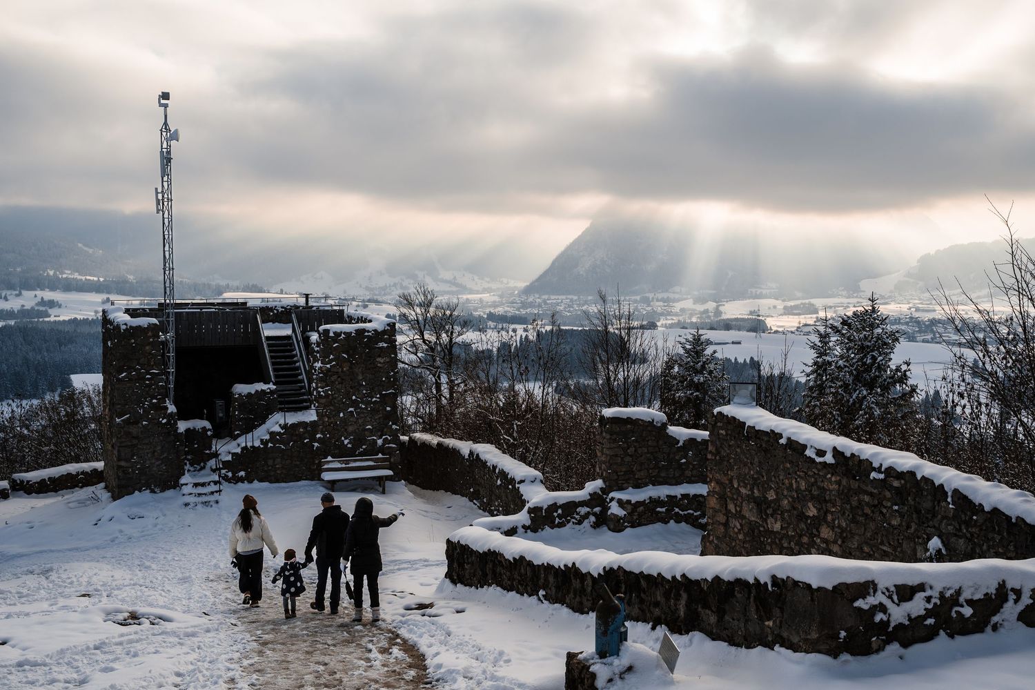 Panoramic winter landscape showing snowy hills and communication towers under cloudy skies.