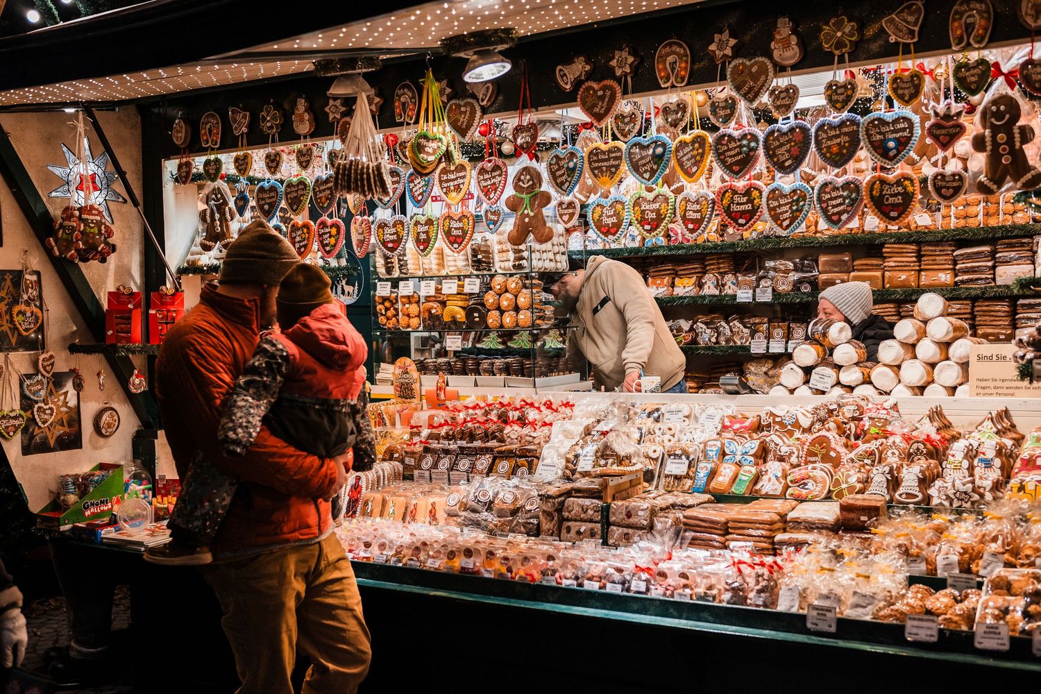Illuminated display of traditional Venetian carnival masks and decorative items at a market stall in Venice.