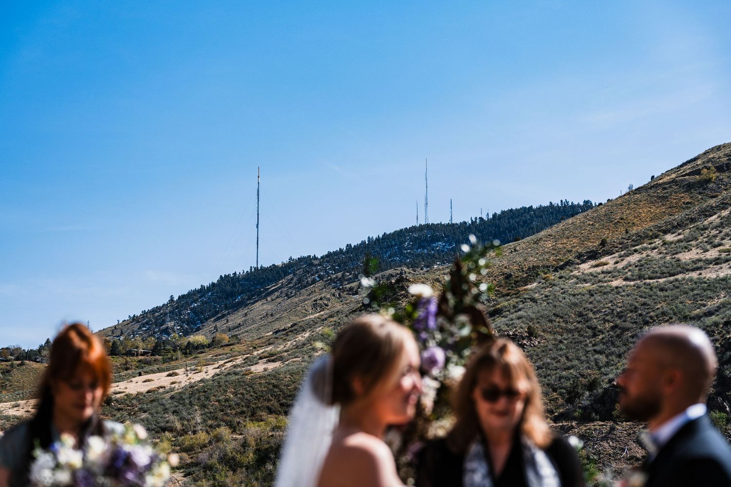 Bride and groom share a blurred moment with mountain landscape and radio towers in background.