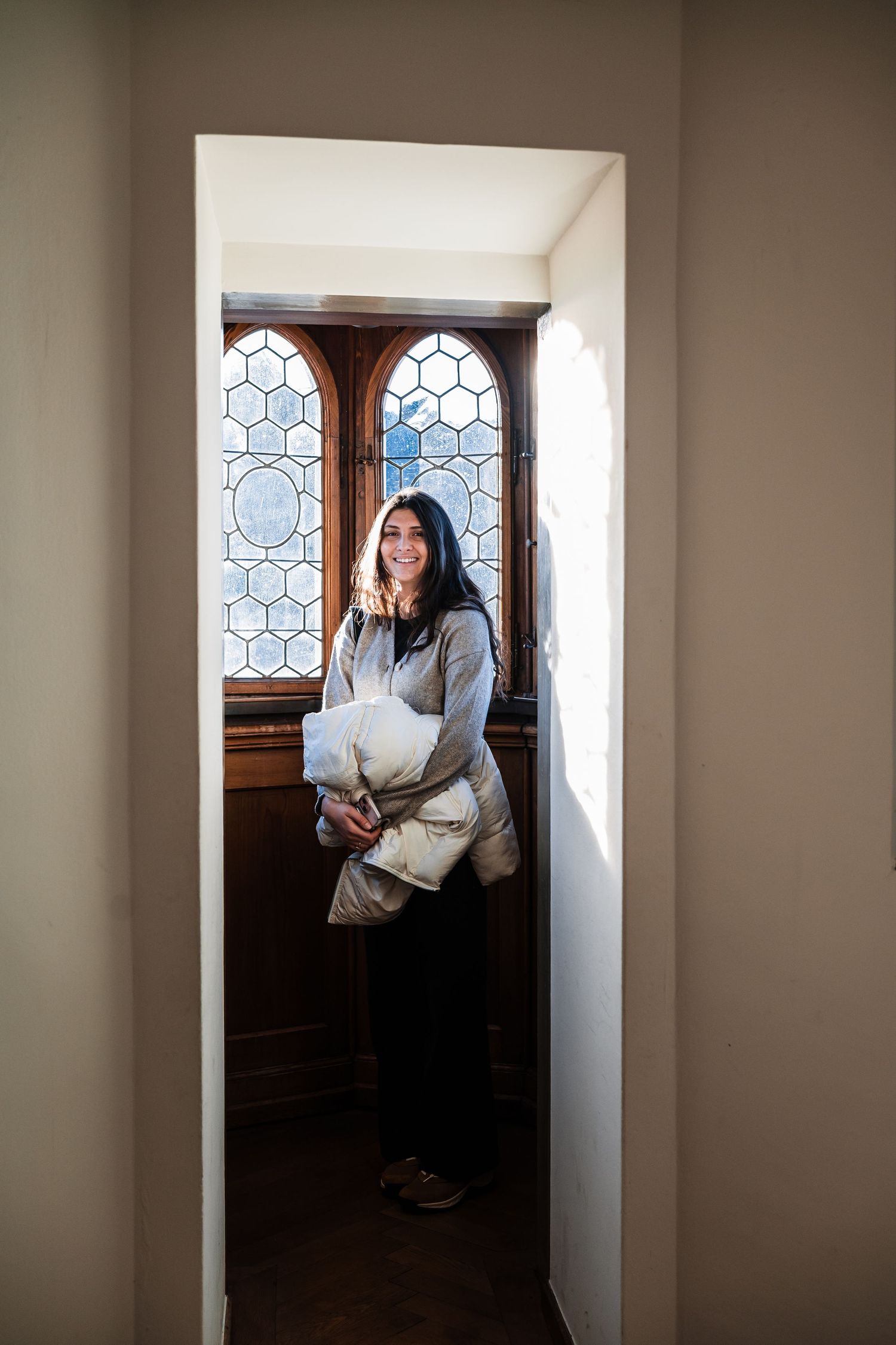 A series of three photos showing a person standing in a sunlit hallway with decorative windows.