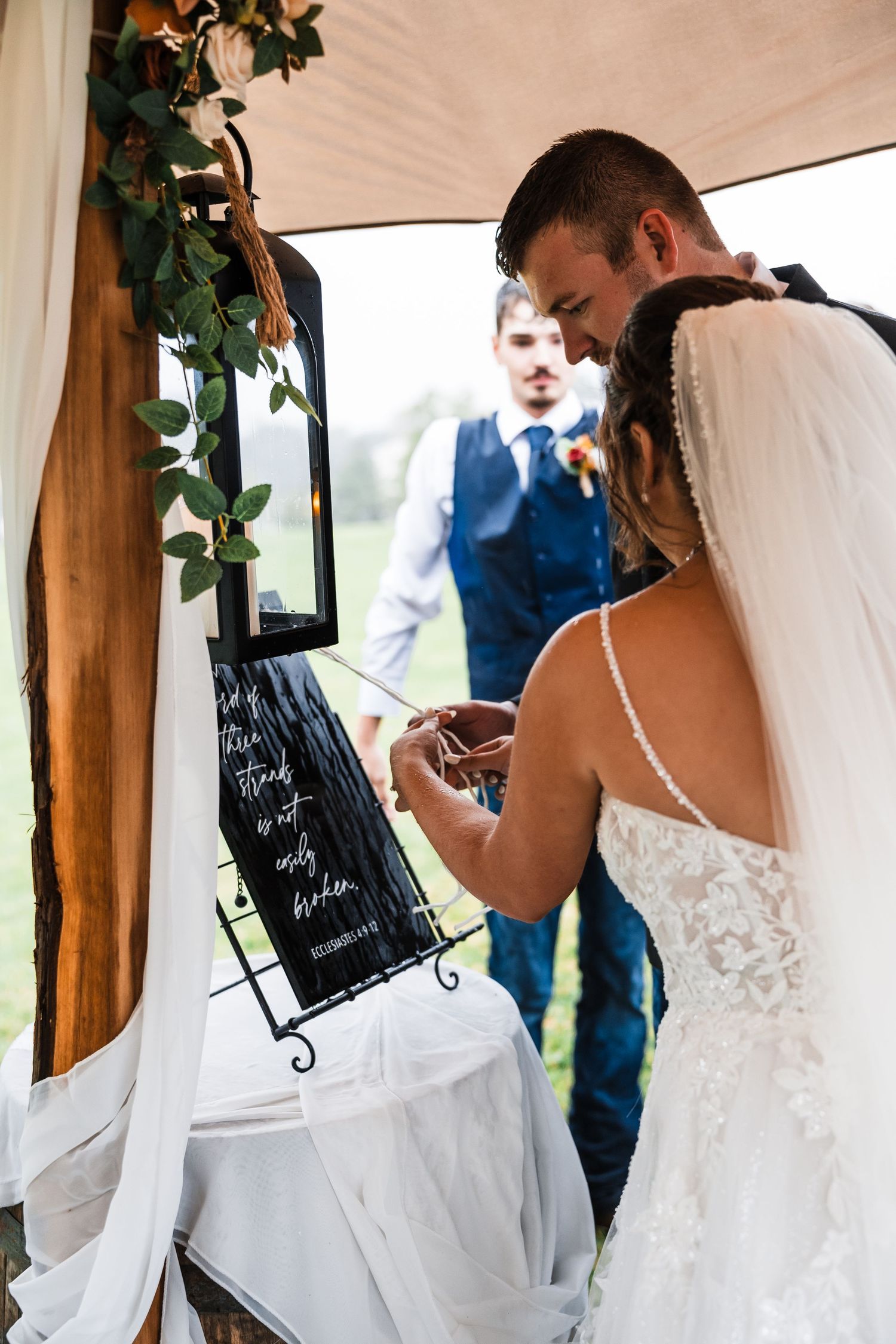 Wedding reception details showing decorative greenery and signage in a rustic indoor venue.