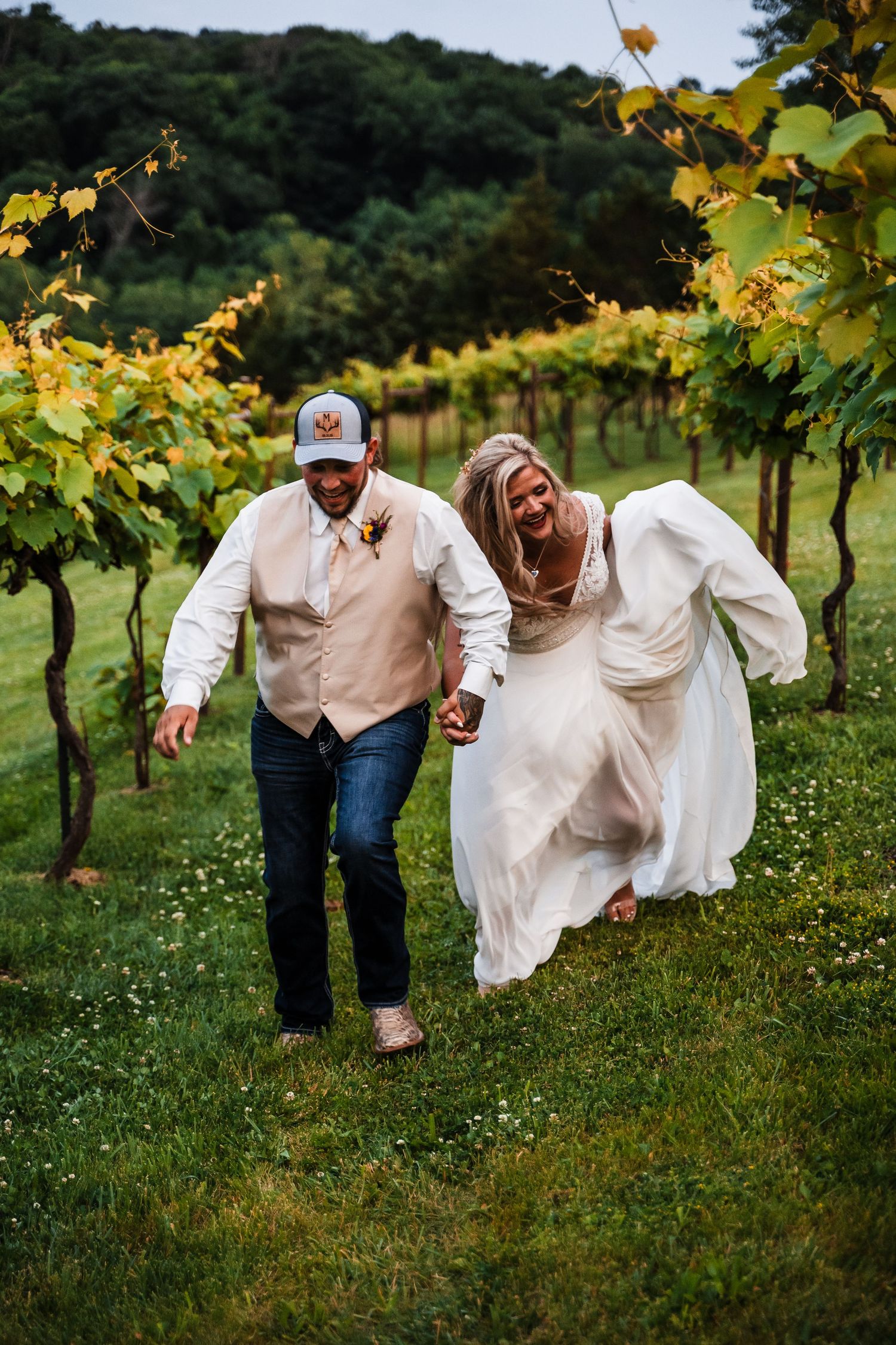 Playful wedding photos taken in a scenic vineyard with rolling hills in the background.