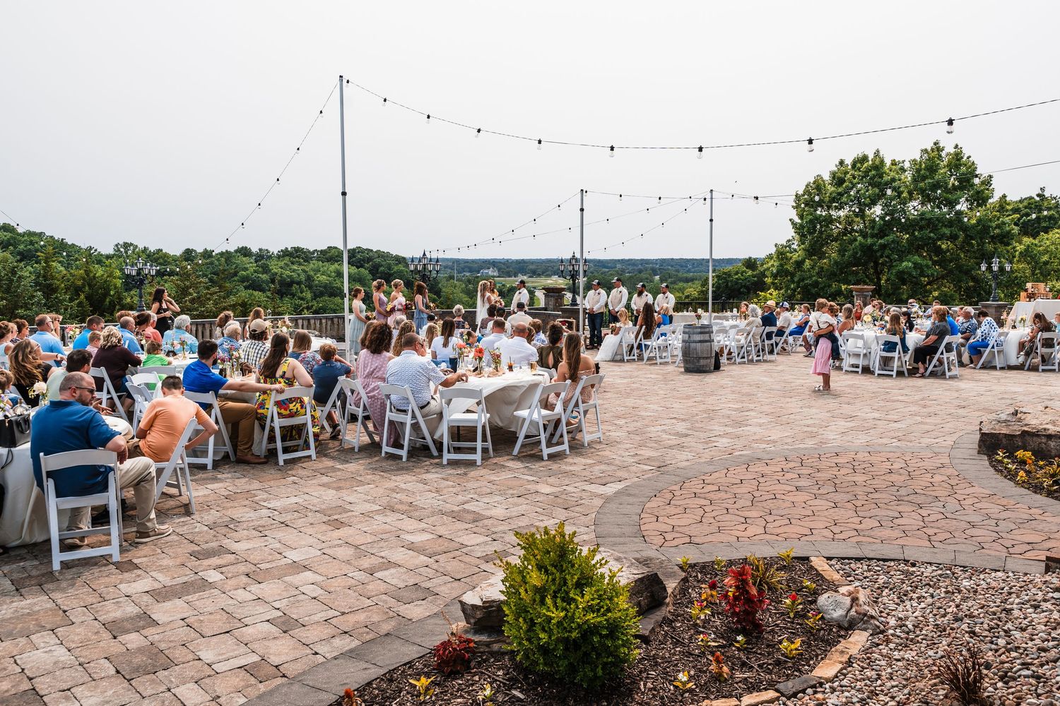 Outdoor wedding reception venue with string lights and stone patio seating.