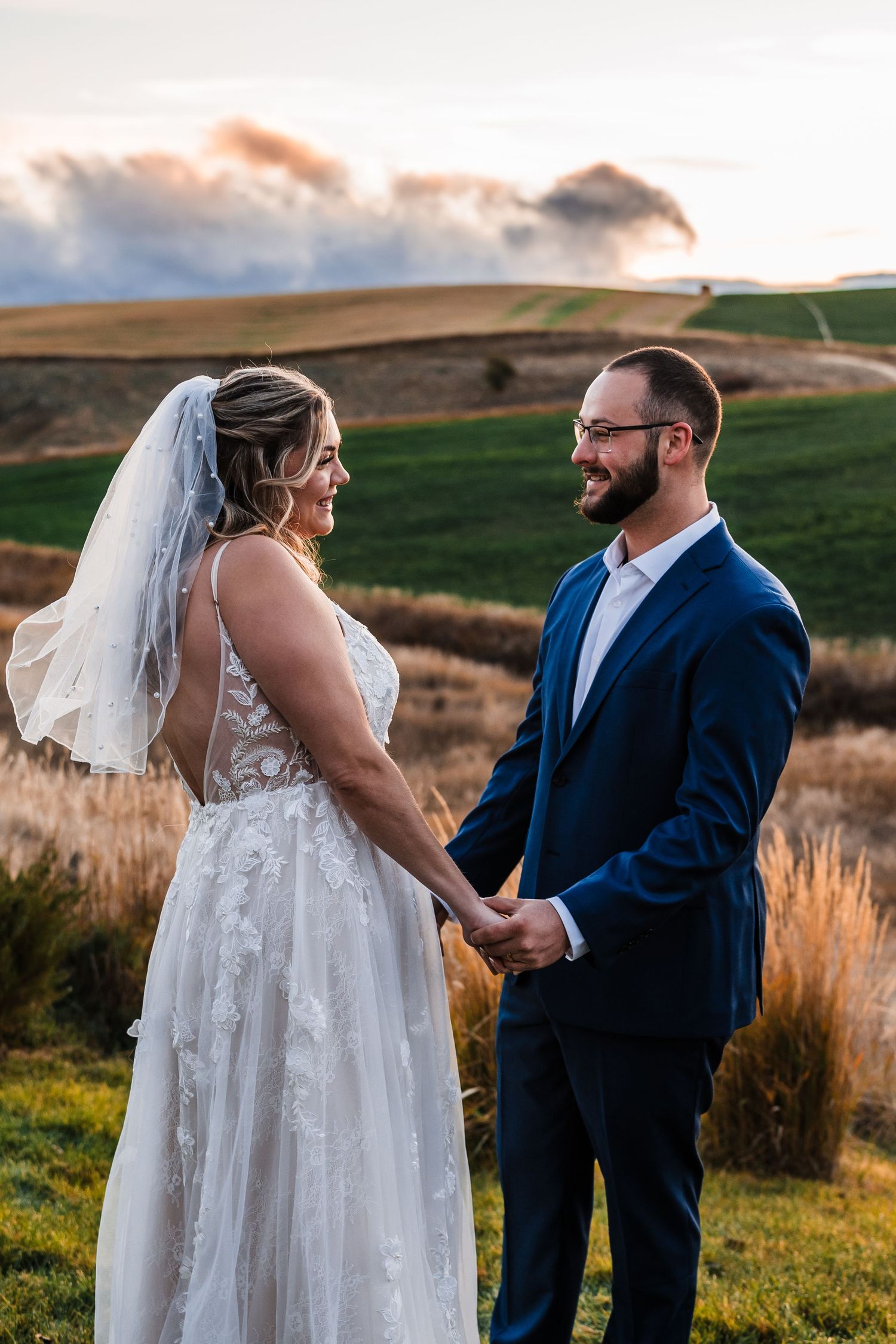 A romantic wedding moment captured in golden light with mountains and rolling hills in the background.