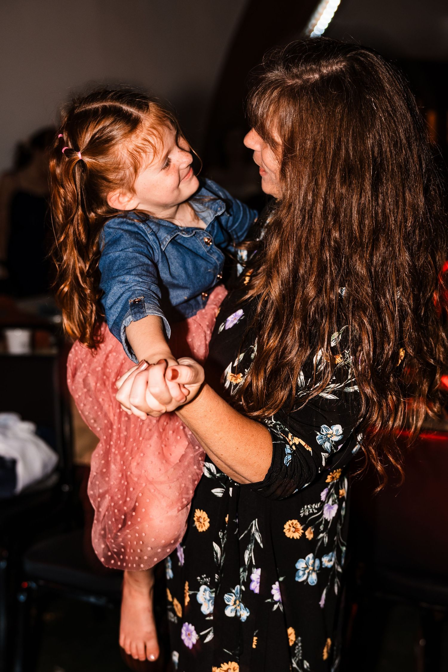 Sweet moment of dancing and twirling in dim lighting at wedding reception.