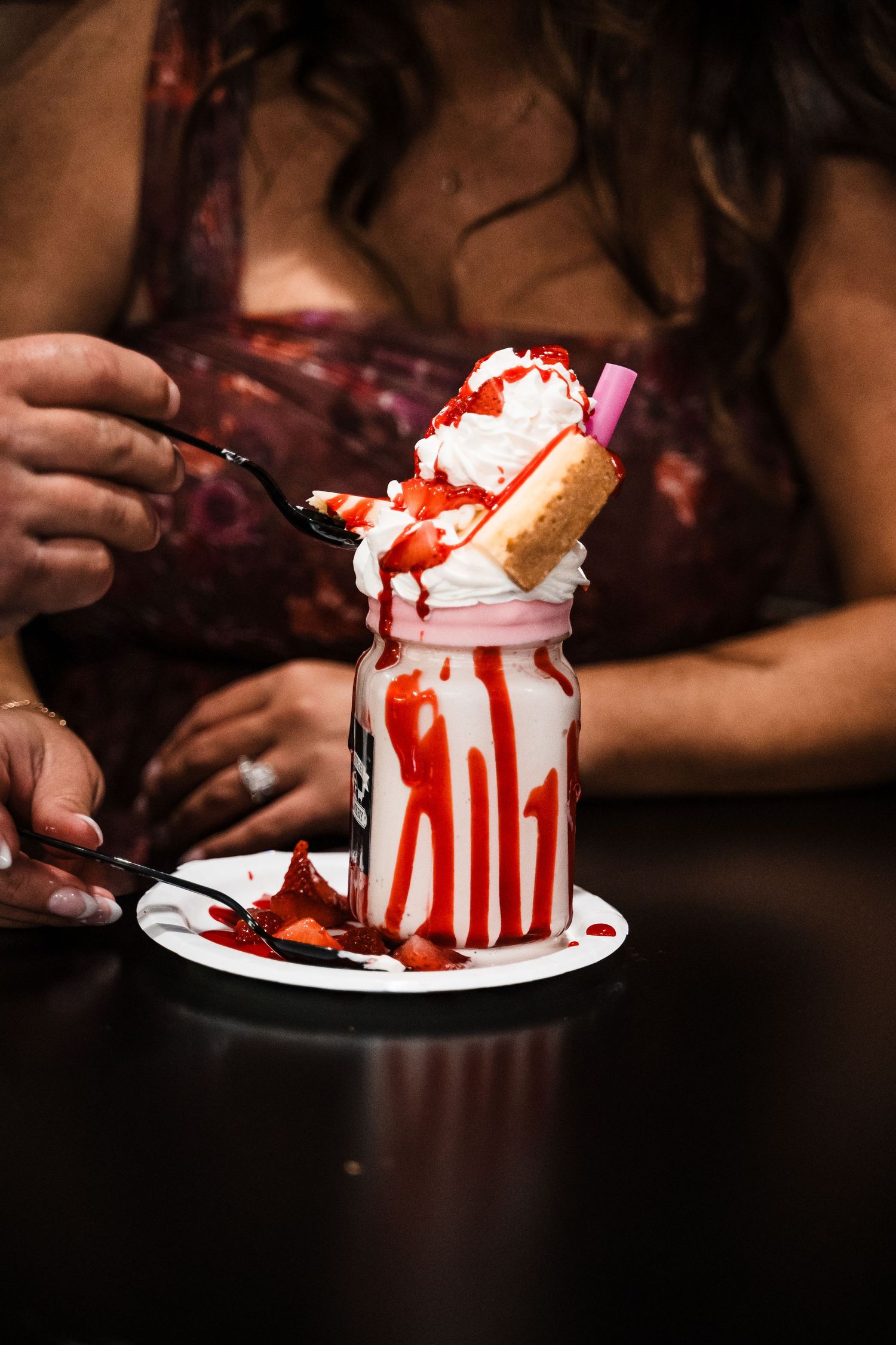 Decadent ice cream sundae with red syrup drizzle served in a mason jar.