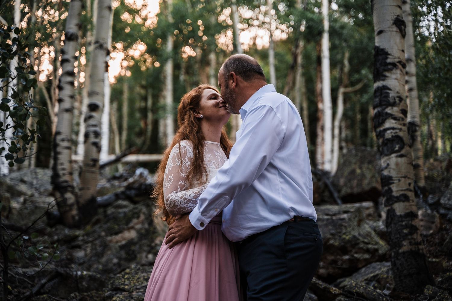 A romantic embrace captured in a serene aspen forest during golden hour.