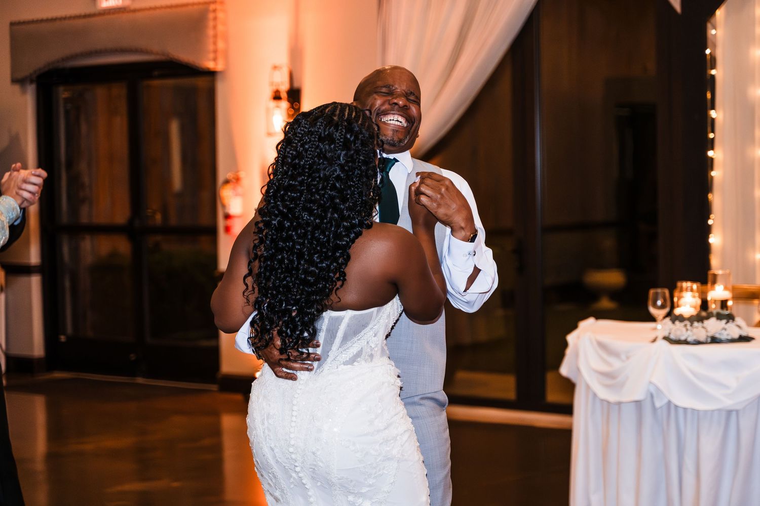 Joyful couple sharing first dance at wedding reception, groom smiling warmly at bride.