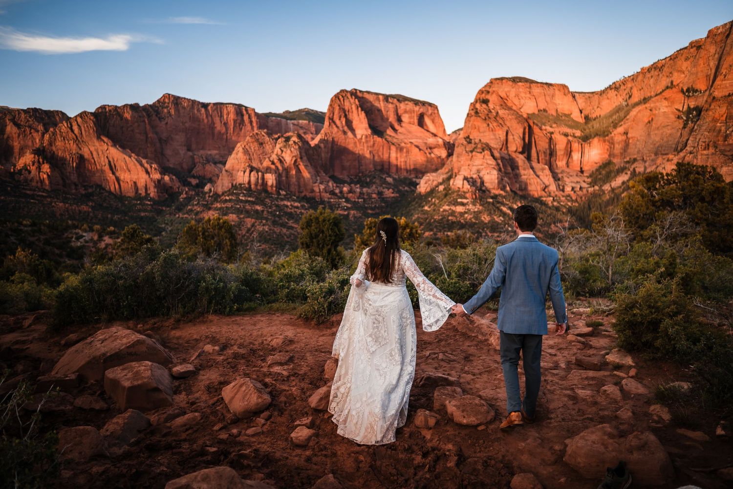 Newlywed couple holding hands facing red rock canyon landscape at sunset in Sedona Arizona desert elopement.