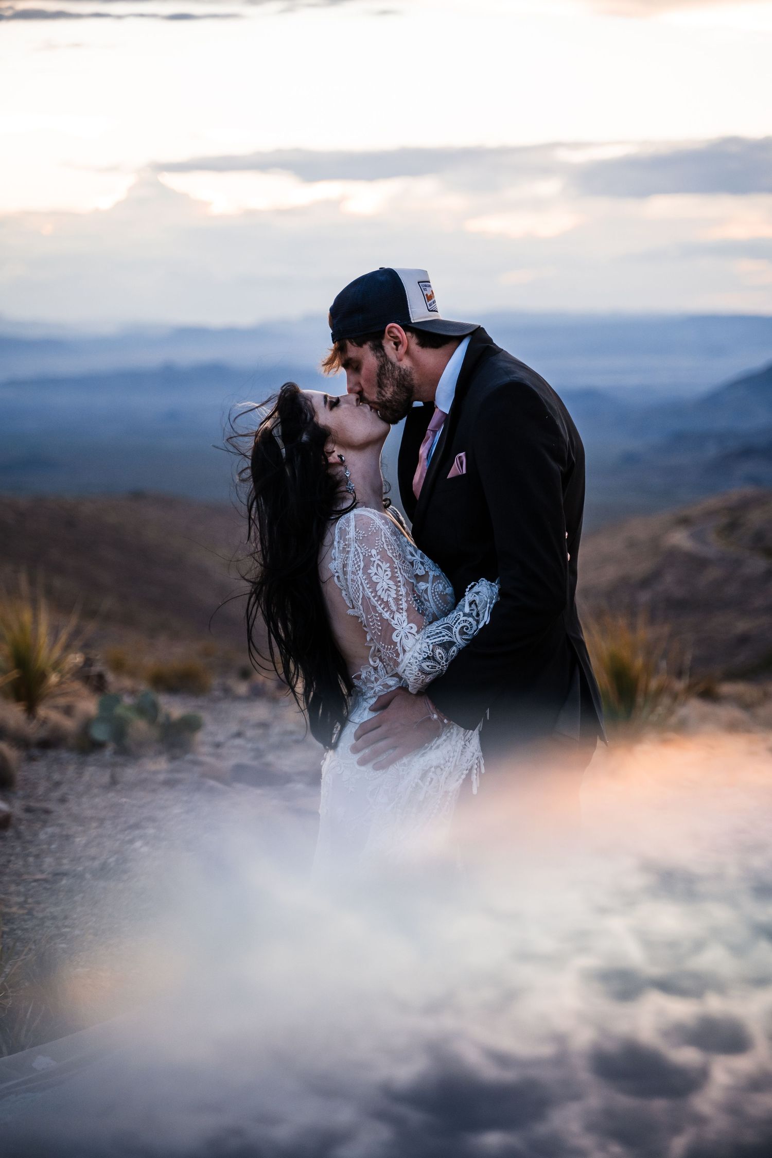 Romantic wedding couple sharing an intimate moment at sunset with misty mountain landscape in the background.