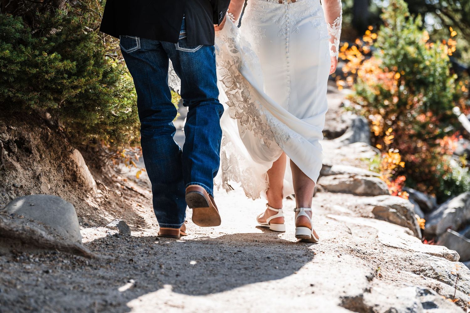 Detail shot of wedding attire and footwear as couple walks on rocky terrain.