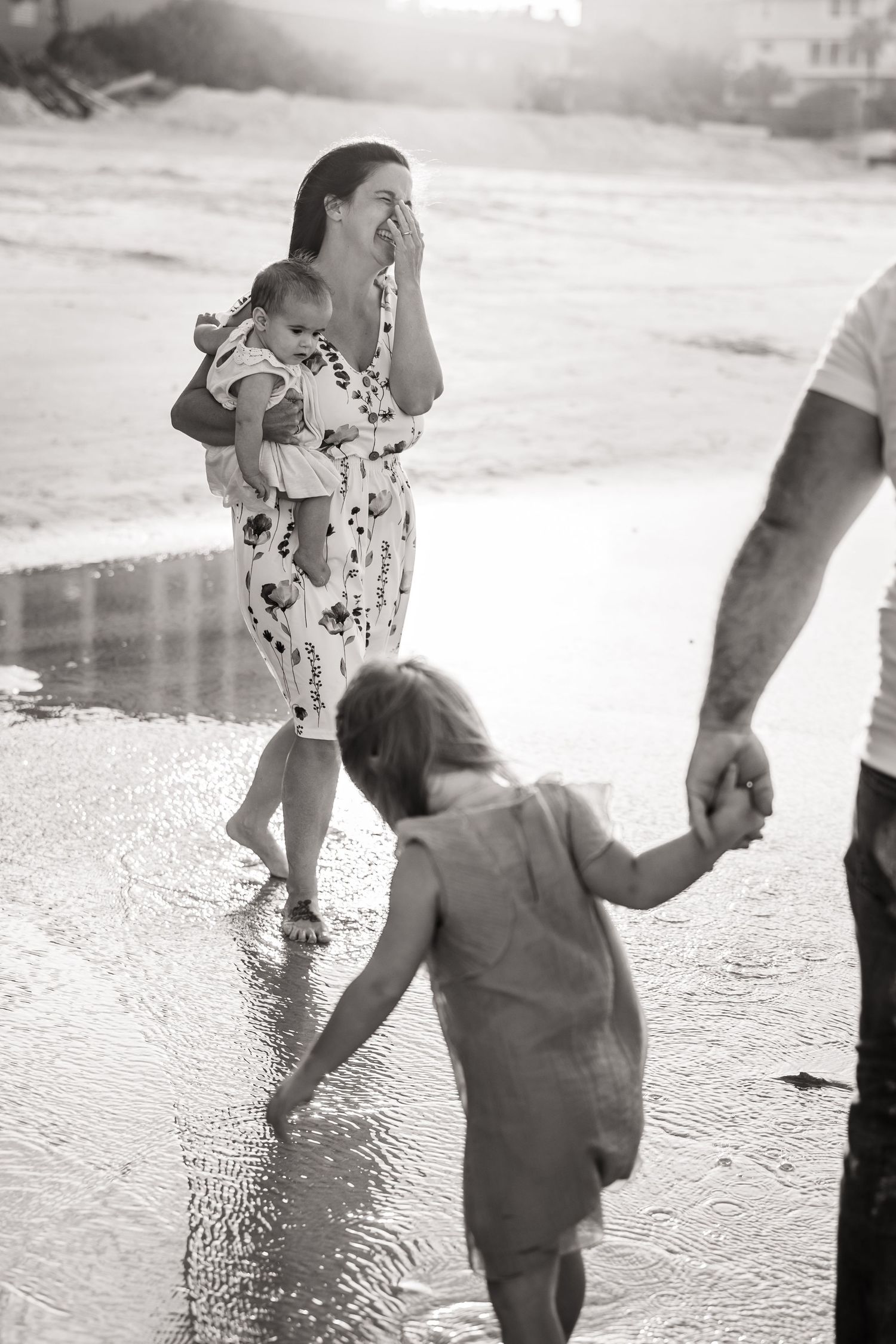 Black and white photo sequence of people splashing and playing in shallow water at the beach.