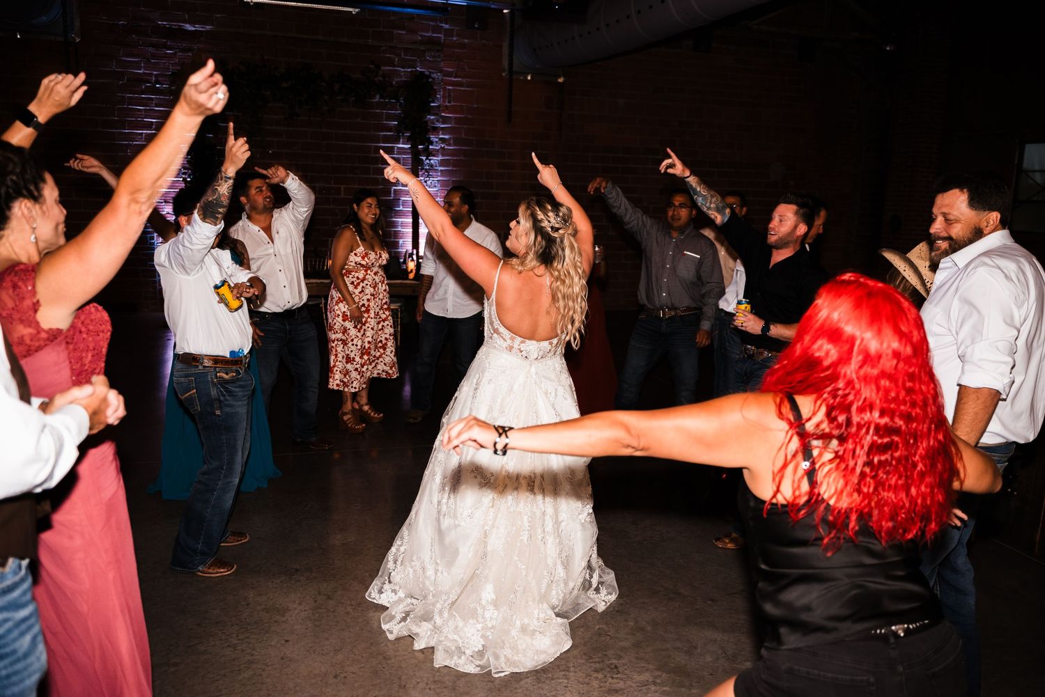 Wedding guests dance energetically on the dance floor during reception celebrations.