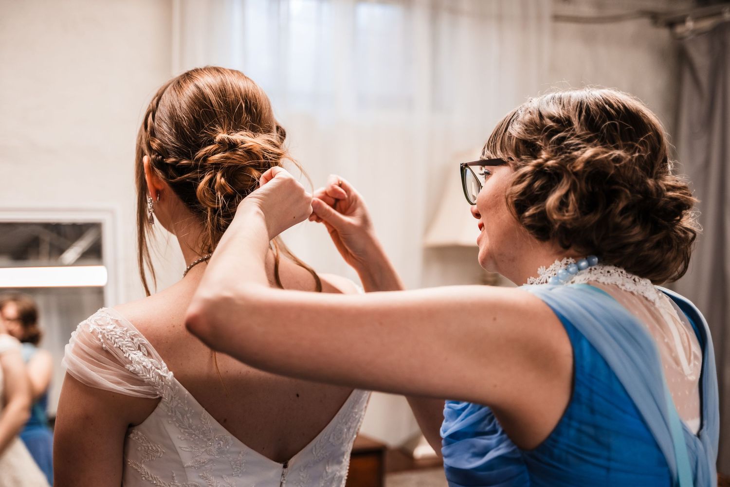 Wedding preparations show final touches being made to a bride's gown in a getting ready room.