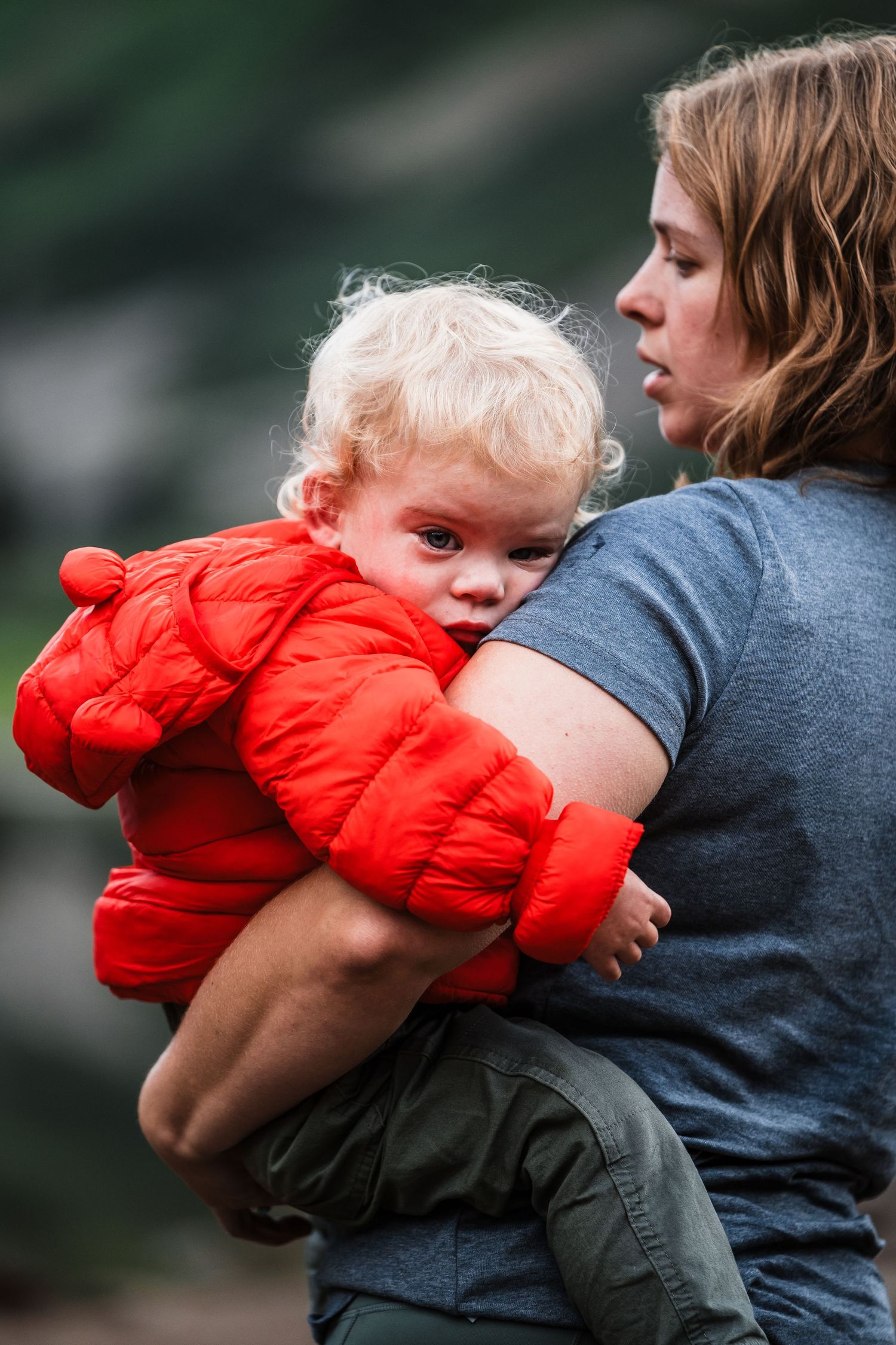 A nurturing moment outdoors with a small child in a bright red winter coat.