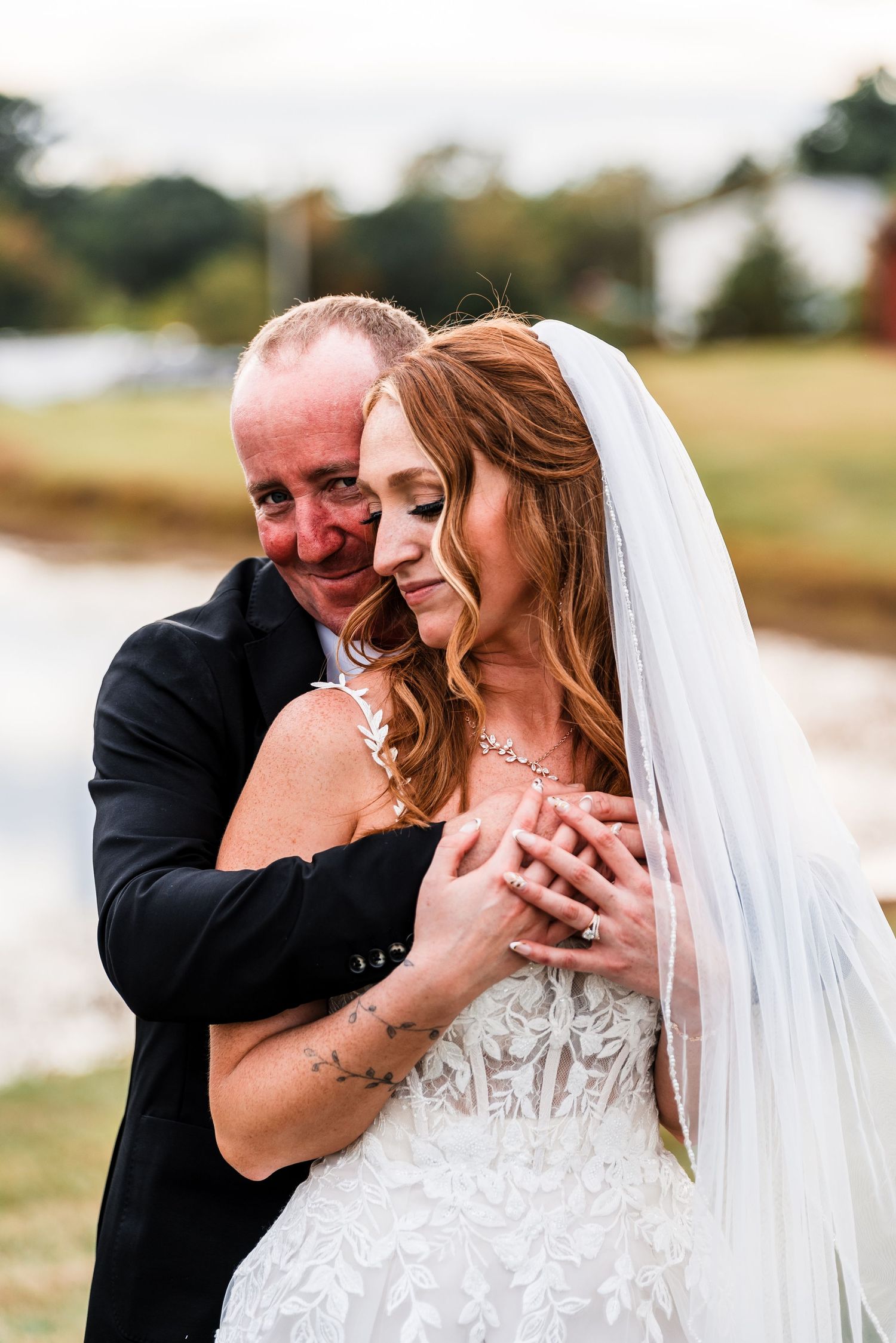 A romantic moment between a couple in wedding attire sharing joyful laughter outdoors.