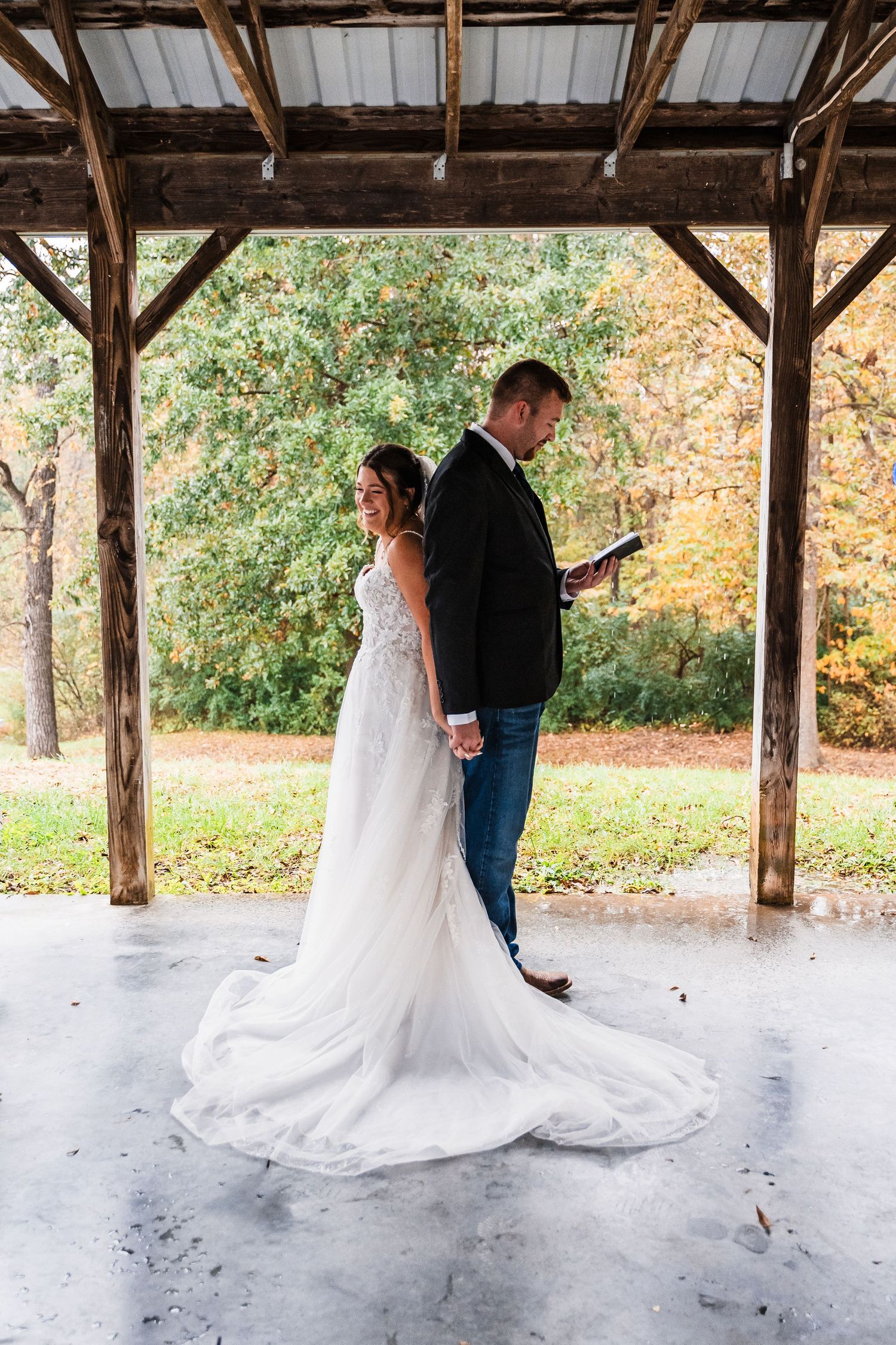 A couple dances together under a rustic wooden pavilion during their autumn wedding.