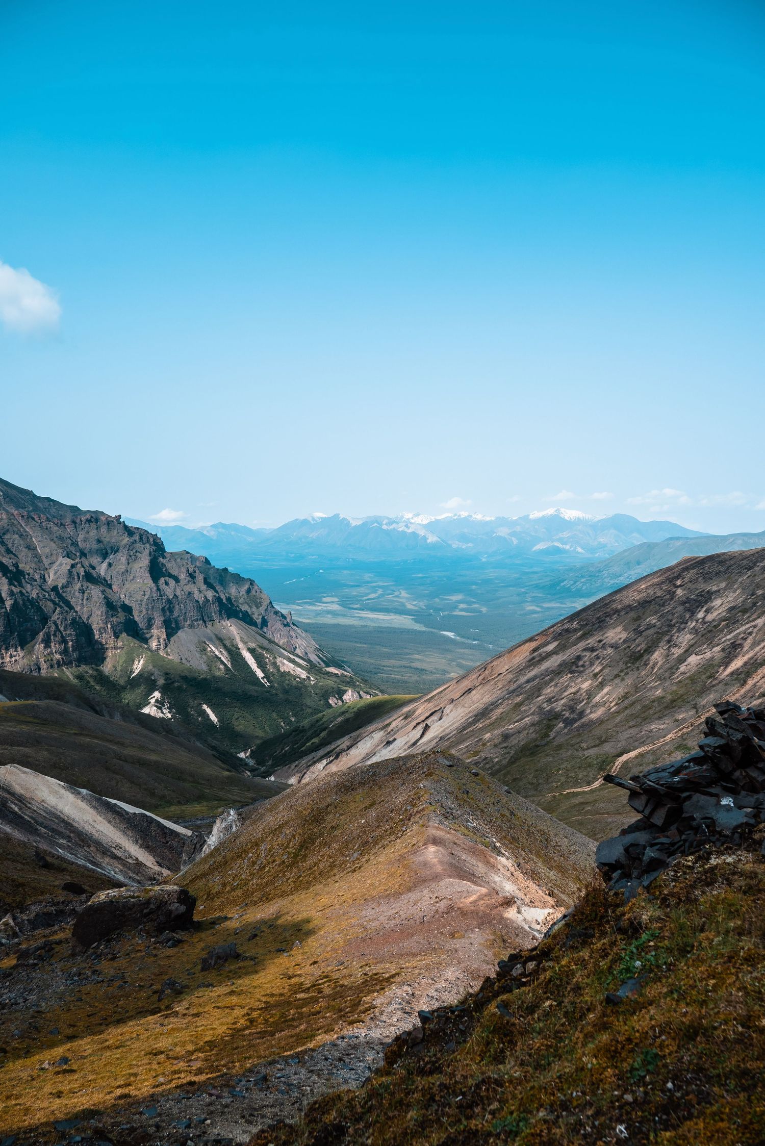 Scenic mountain landscape view with rolling hills and valleys under bright blue sky in rugged mountainous terrain.
