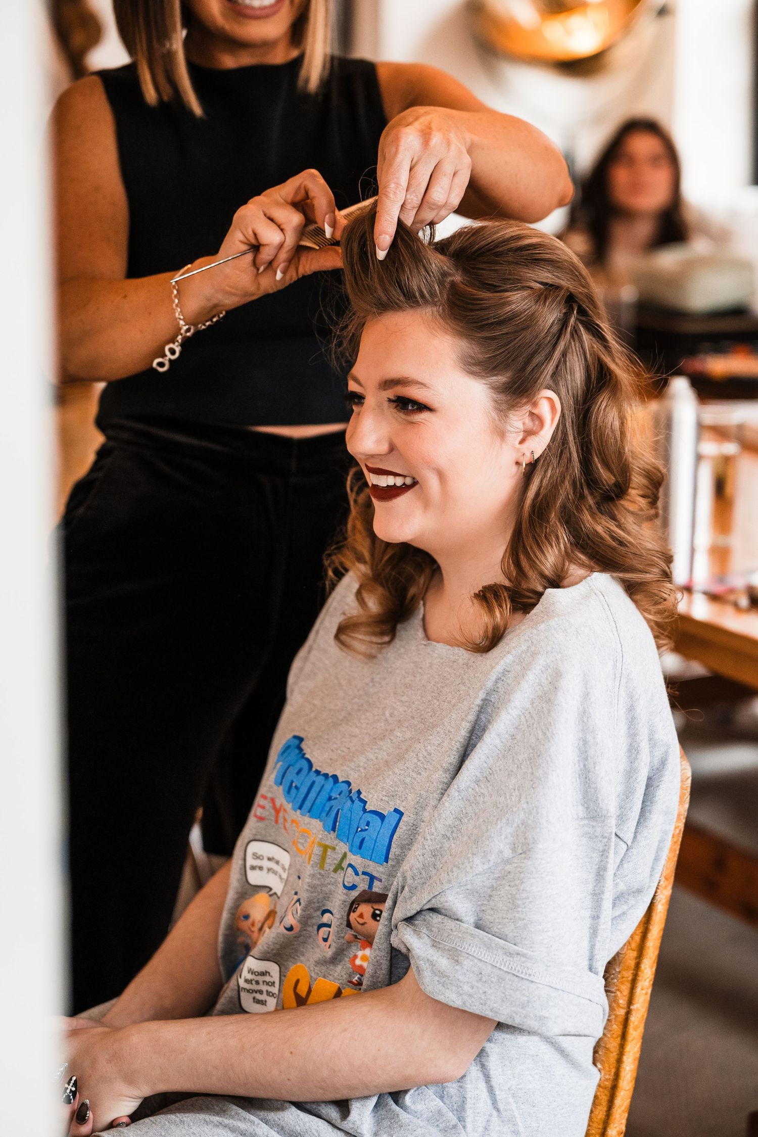 Candid shots of someone laughing and smiling while sitting in a wooden chair wearing a casual grey t-shirt.