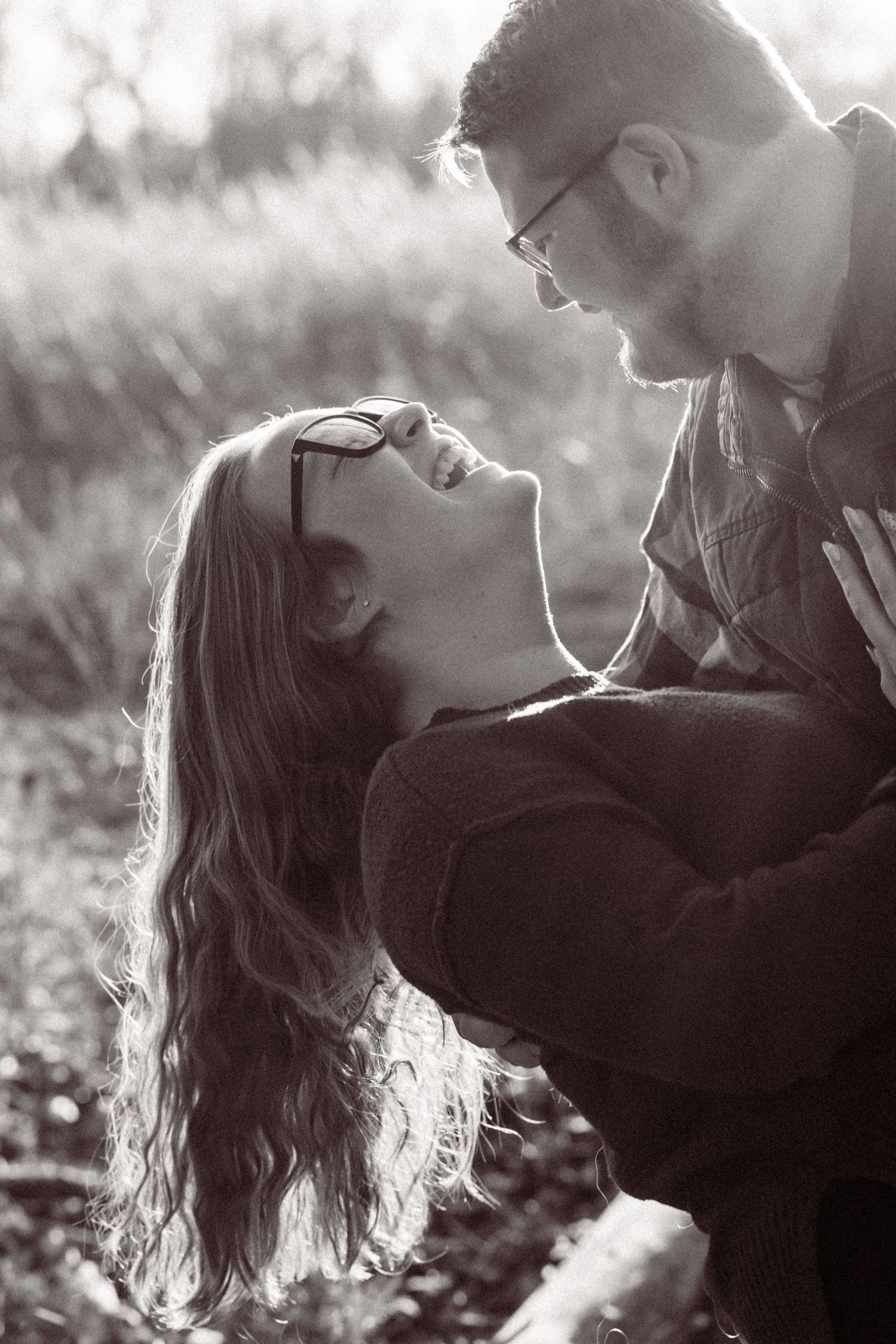 A romantic black and white portrait of a couple sharing an intimate moment outdoors in soft natural lighting.