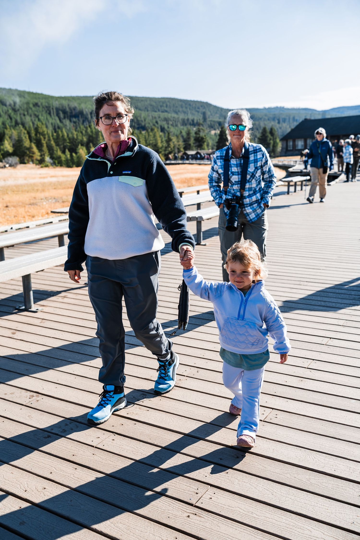 Family walking together on a wooden boardwalk at a national park on a sunny day.