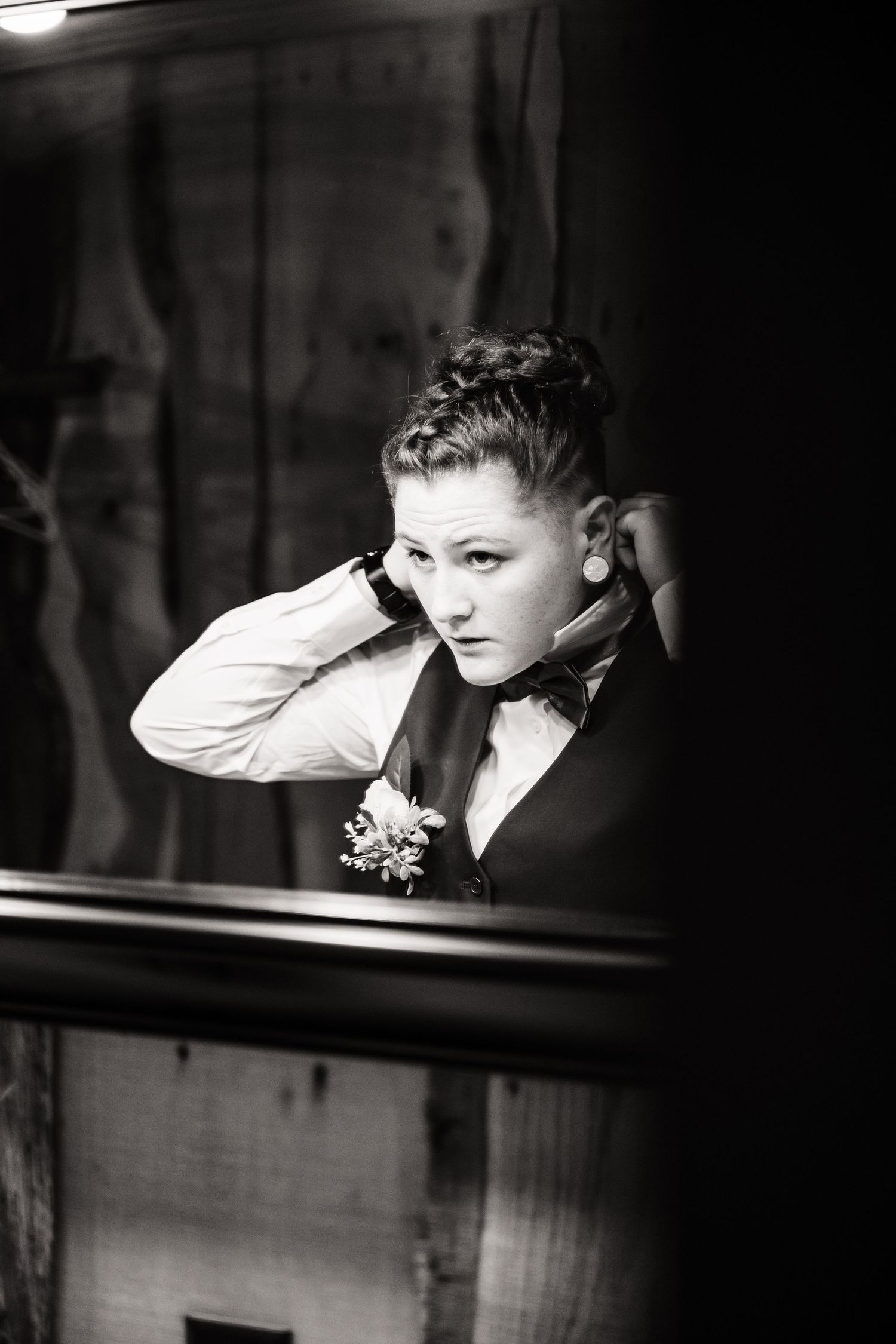 A dramatic black and white portrait in moody lighting shows a formal attire with a corsage.