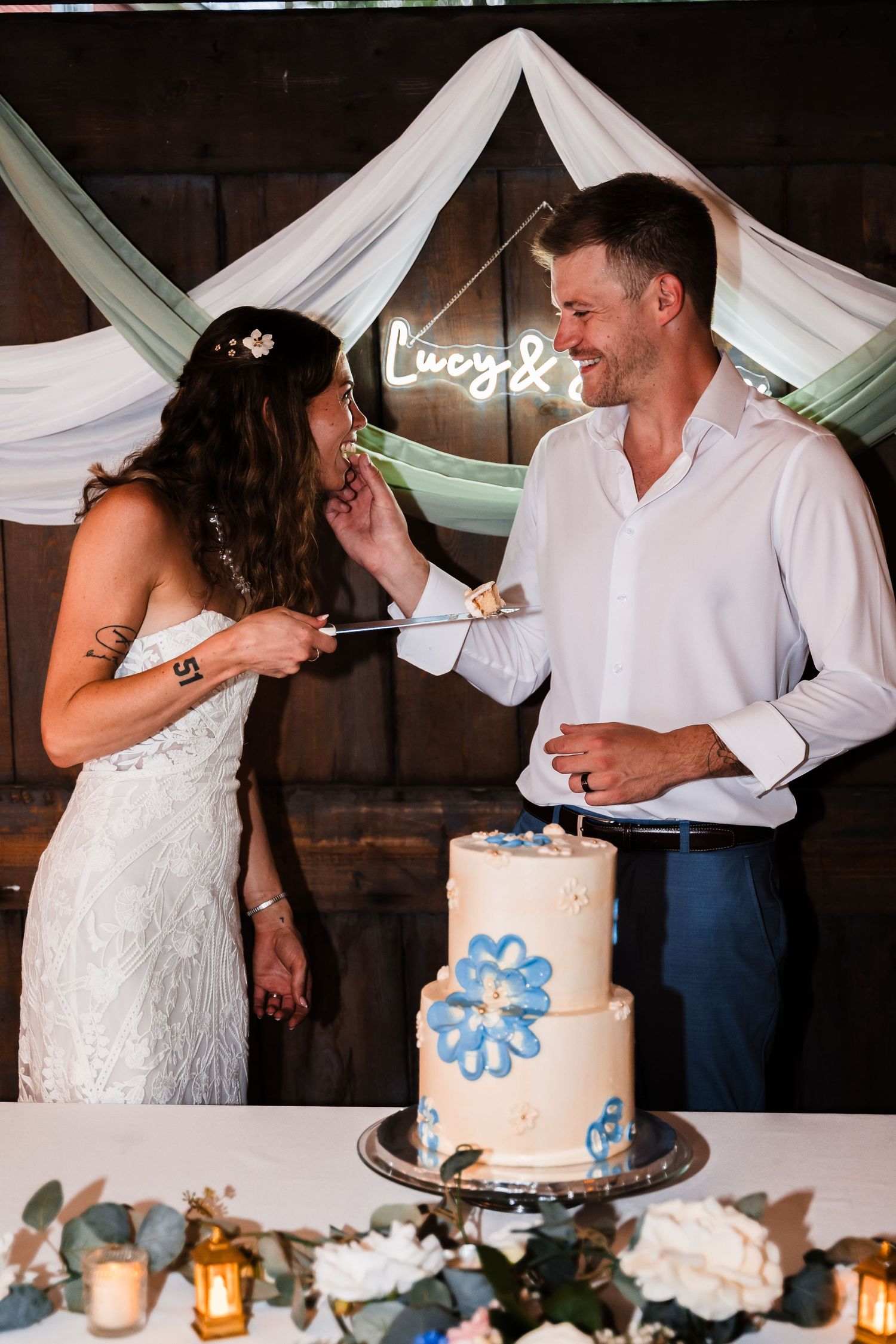 Playful cake-feeding moment between newlyweds at their reception.