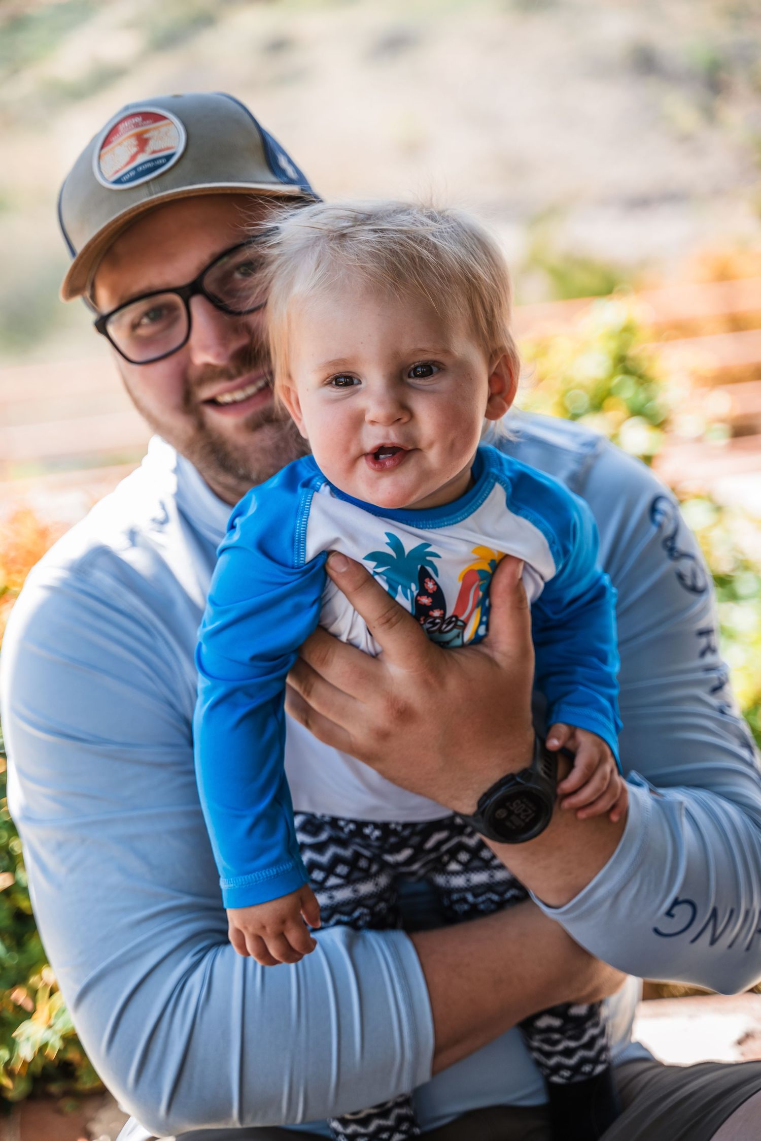 A parent and toddler share a joyful outdoor moment together while wearing casual attire on a sunny day.