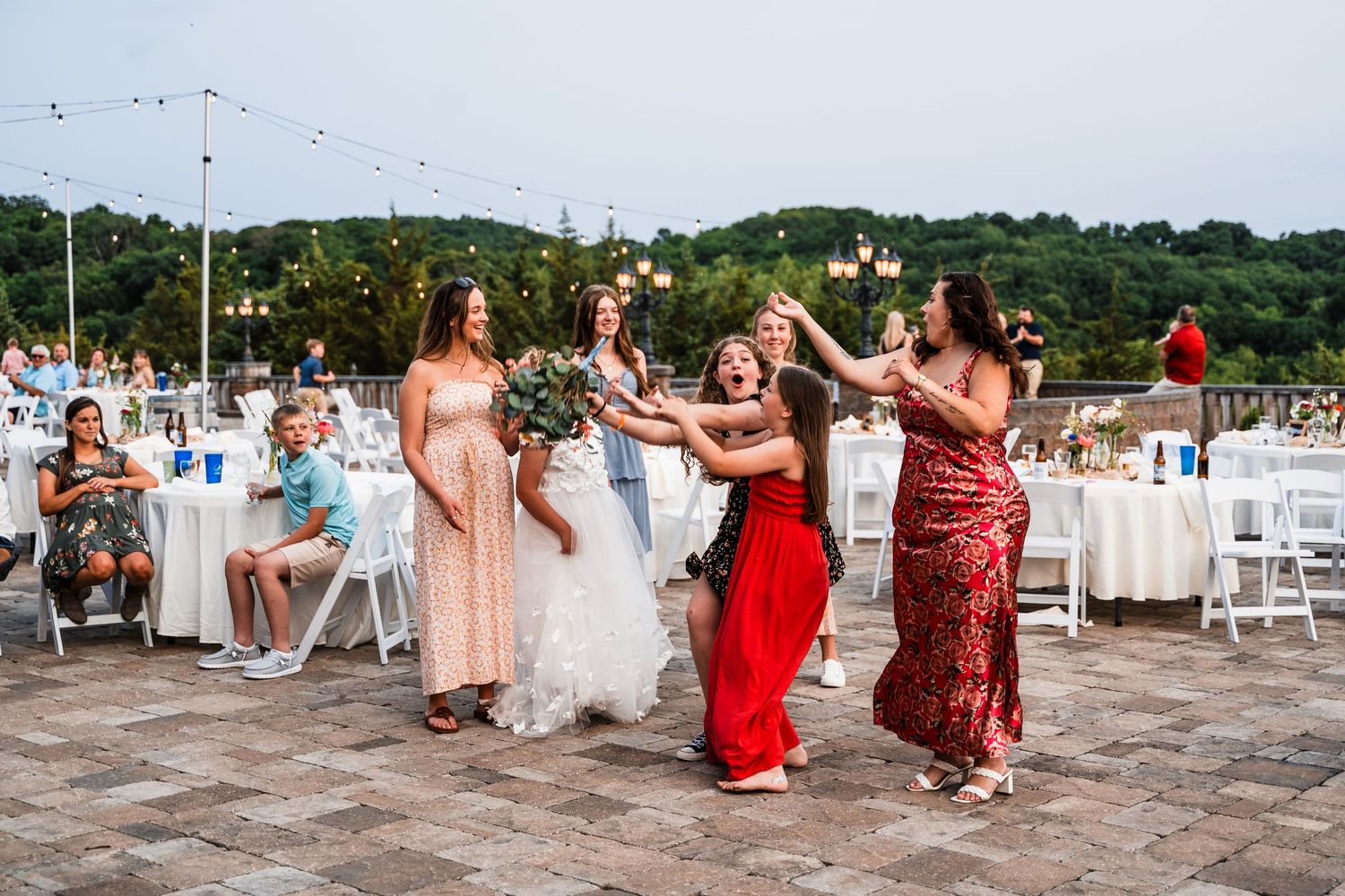 Wedding party dancing and enjoying celebrations during an outdoor summer reception by the beach.