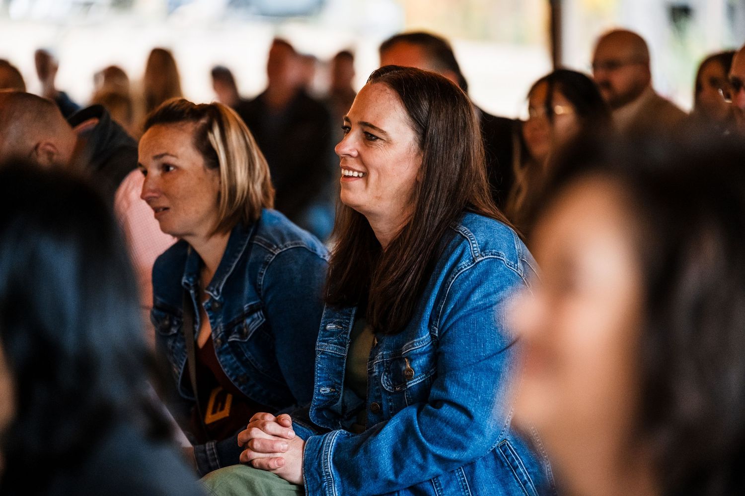 Wedding guests watching and smiling during a celebration event.