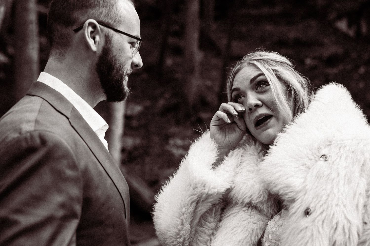 Black and white portrait of couple in wedding attire outdoors.