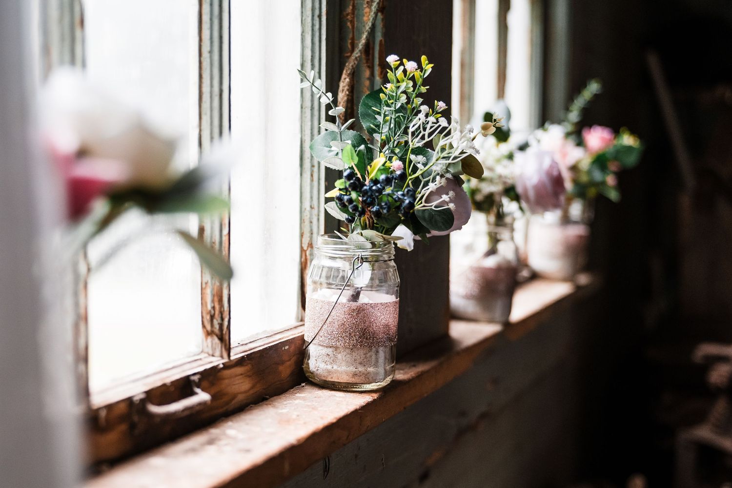 Sunlight streams through a window onto potted plants and flowers on a bright windowsill.