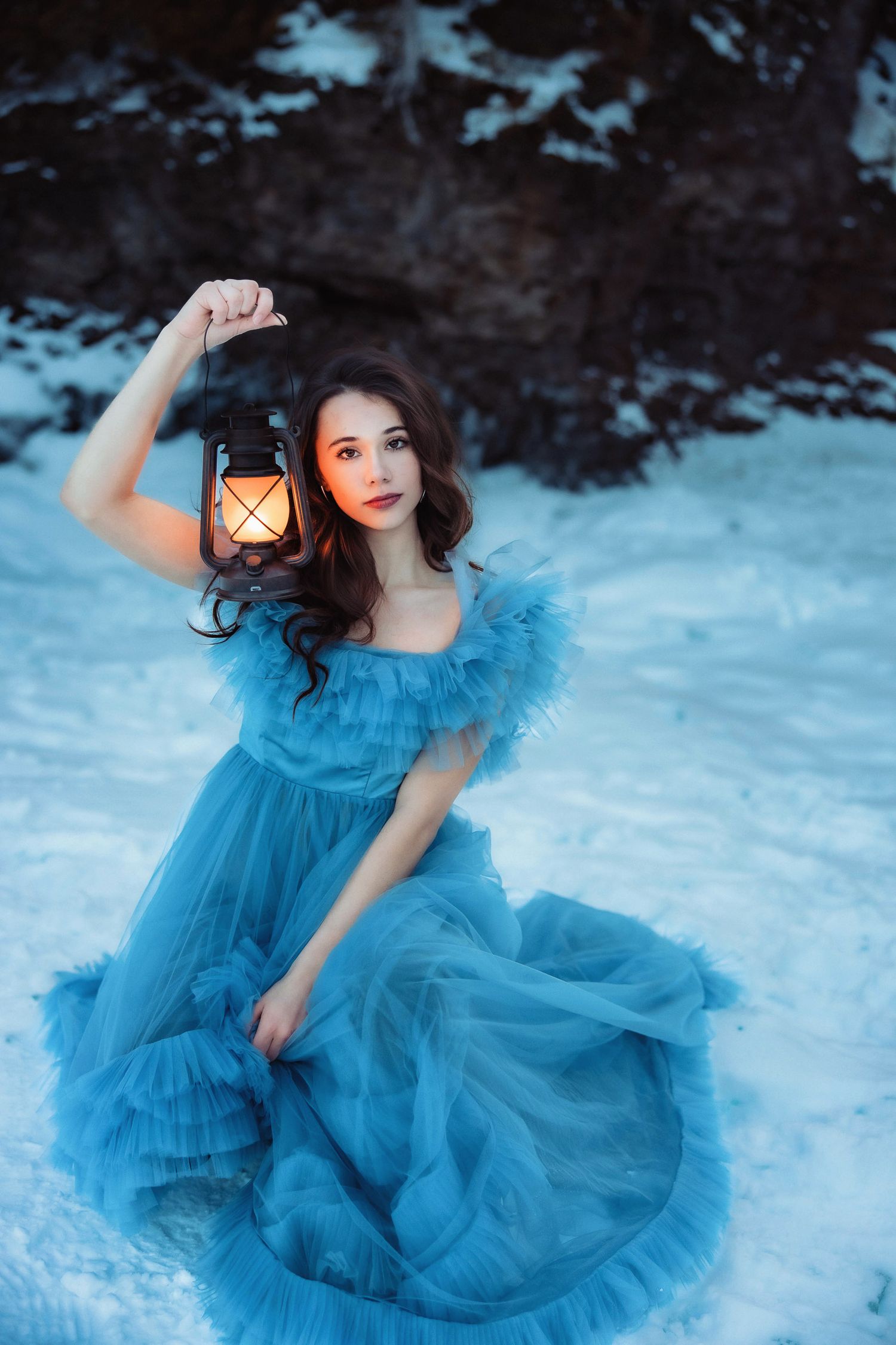 High school senior portrait in the winter at Black Rocks in Marquette, Michigan with a lantern at golden hour.