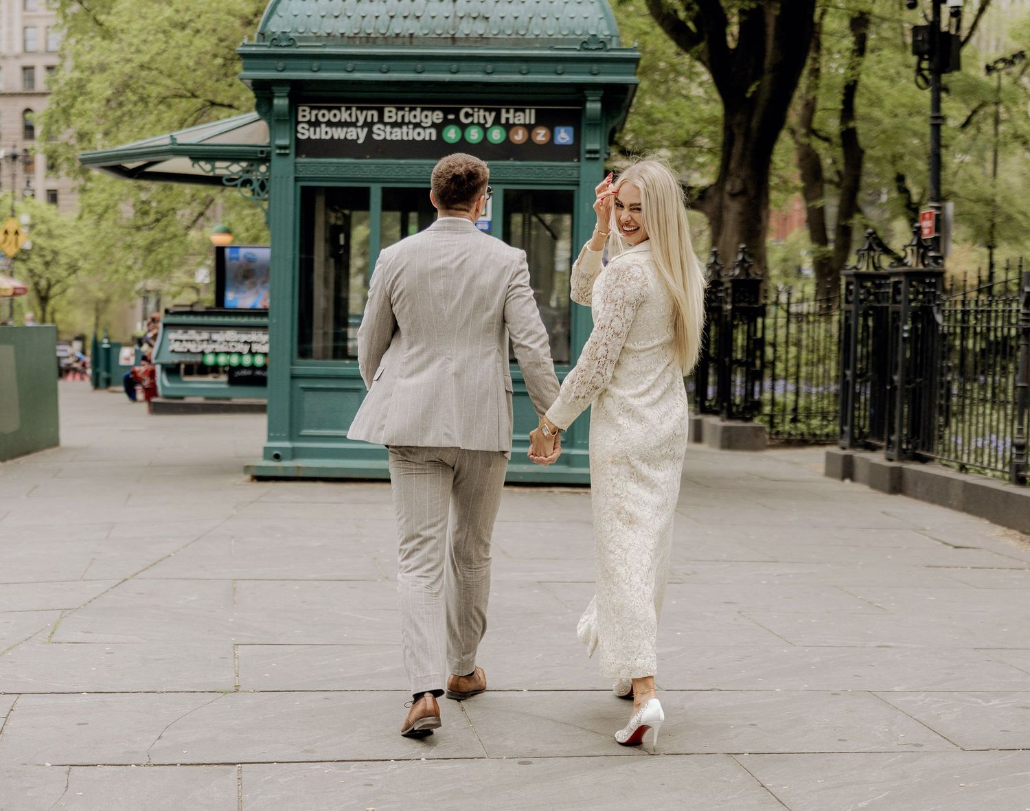 Bride and groom walking down a street in New York City by subway after city hall elopement.