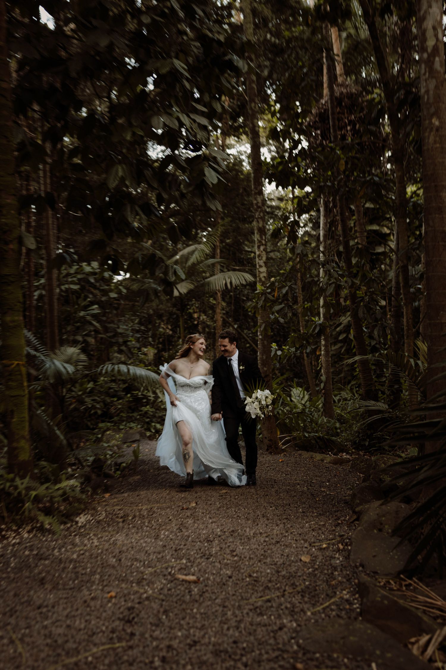 Bride and groom run through the botanical garden after their elopement in kauai, Hawaii.
