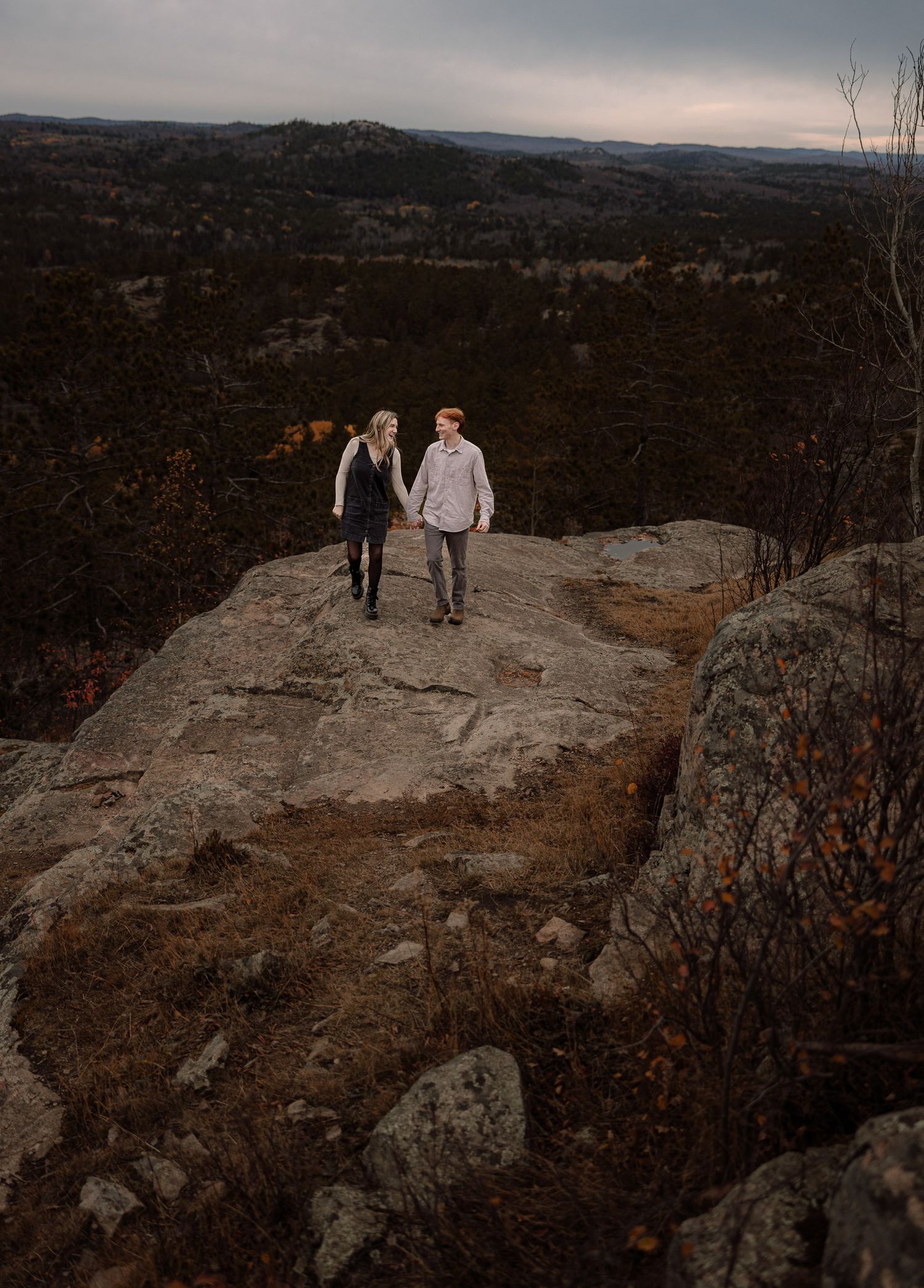 Engagement picture on top of a mountain, couple holding hands, laughing, sugar loaf Marquette, Michigan.
