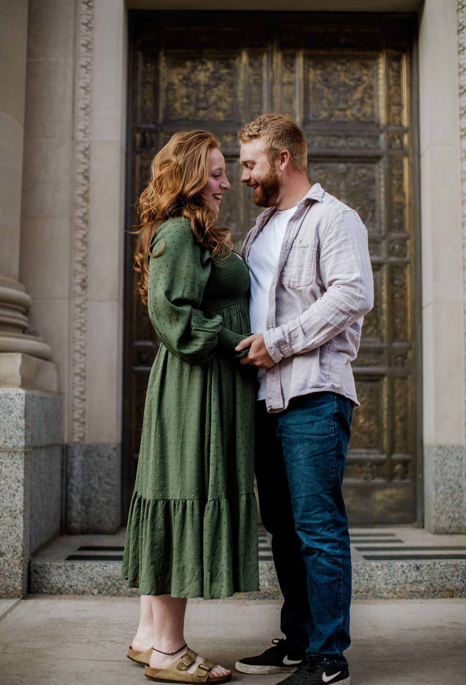 Sunrise engagement pictures downtown Marquette, Michigan. Couple kissing in front of gold doors.
