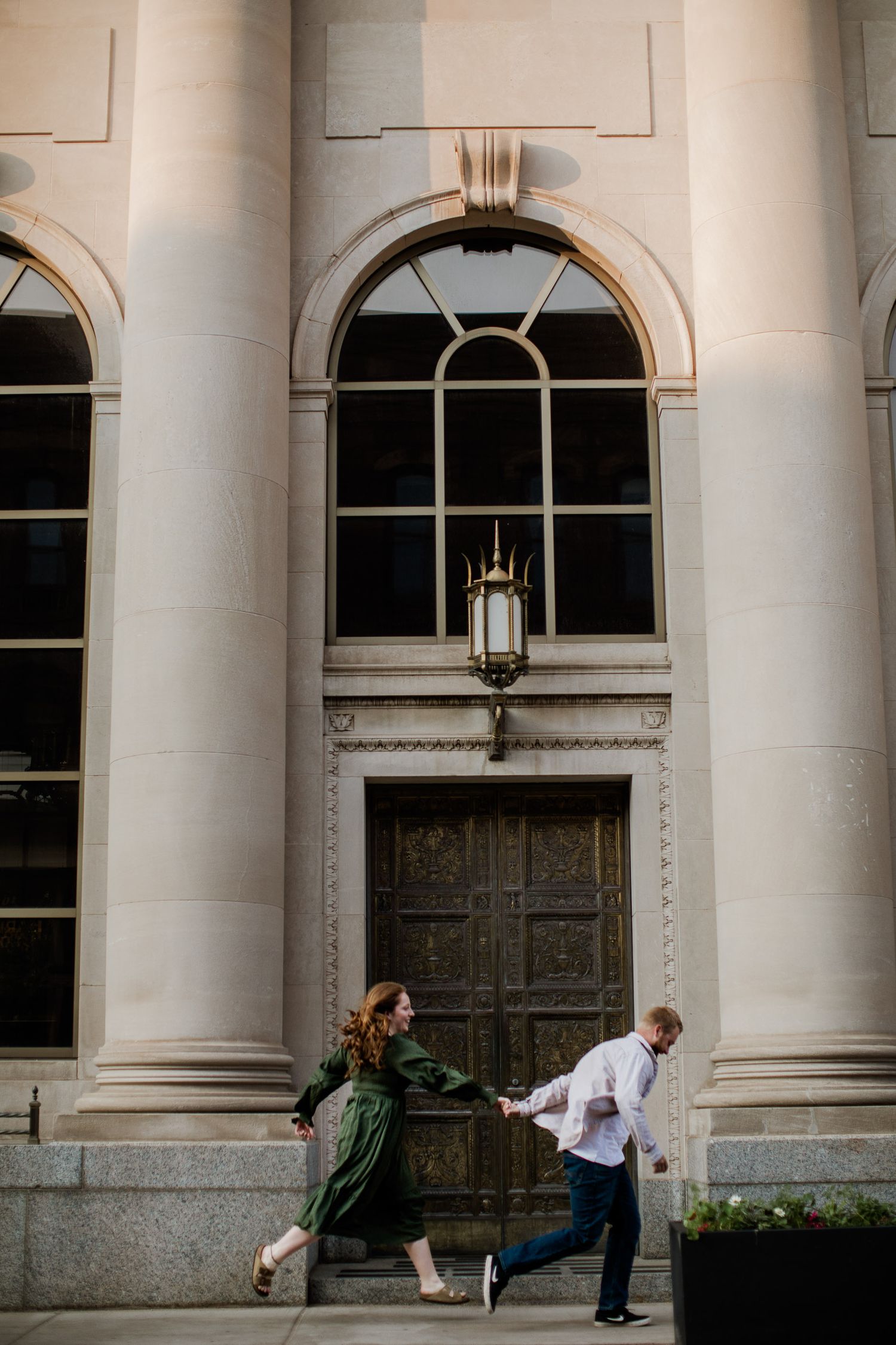 couple running down the street Sunrise engagement pictures downtown Marquette, Michigan.