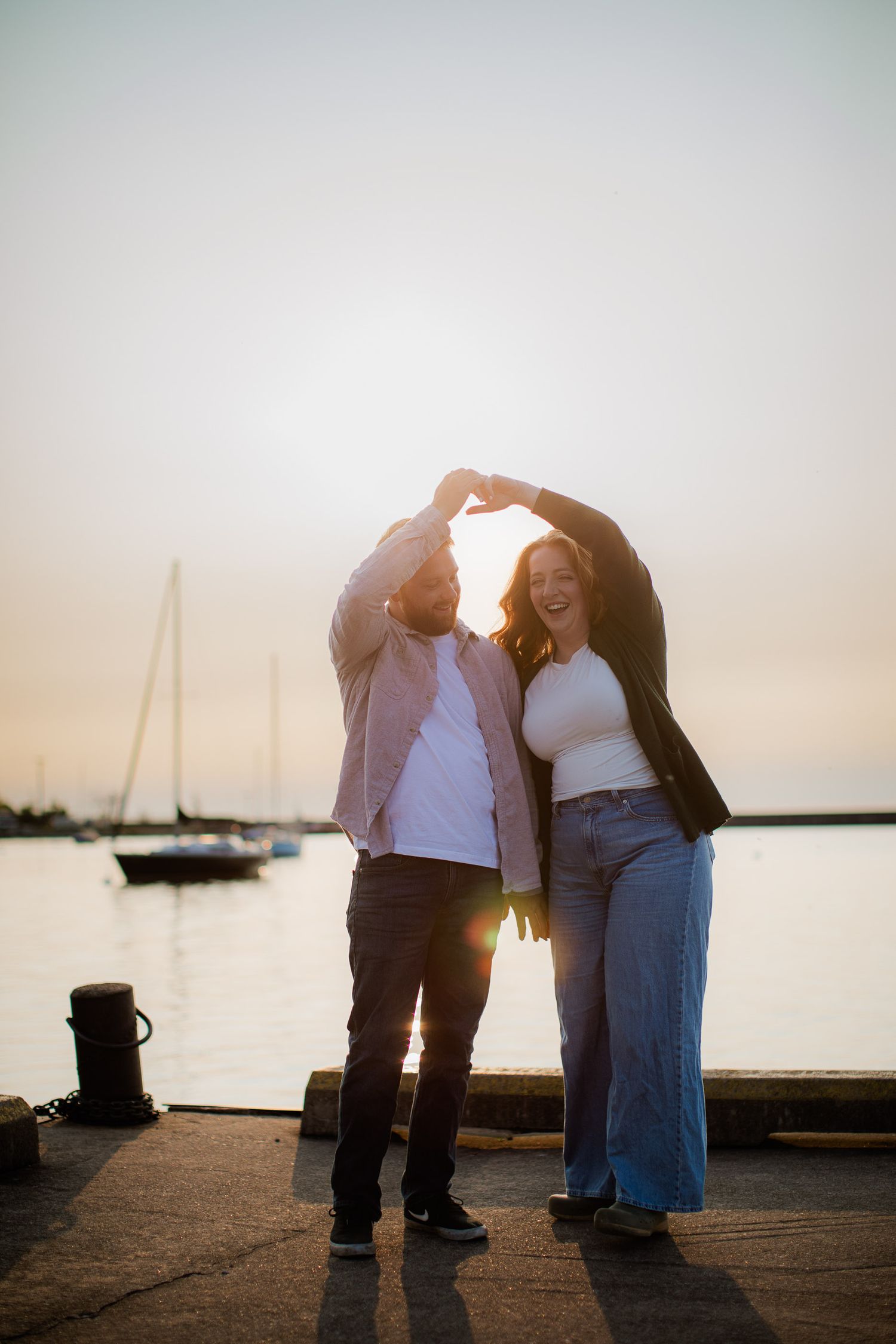 Sunrise engagement pictures downtown Marquette, Michigan. on the Lake Superior shore with sail boats.