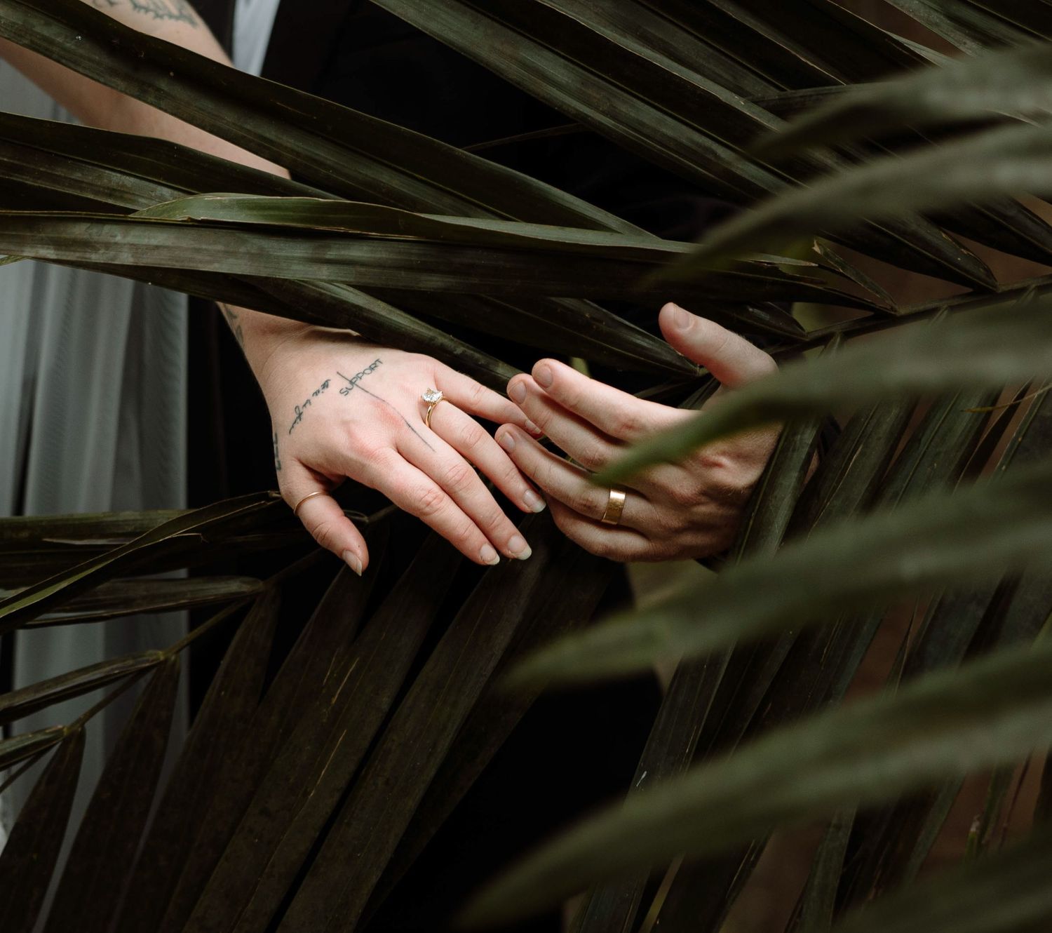 Bride and groom show their rings on a palm tree in a botanical garden in Kauai, Hawaii.