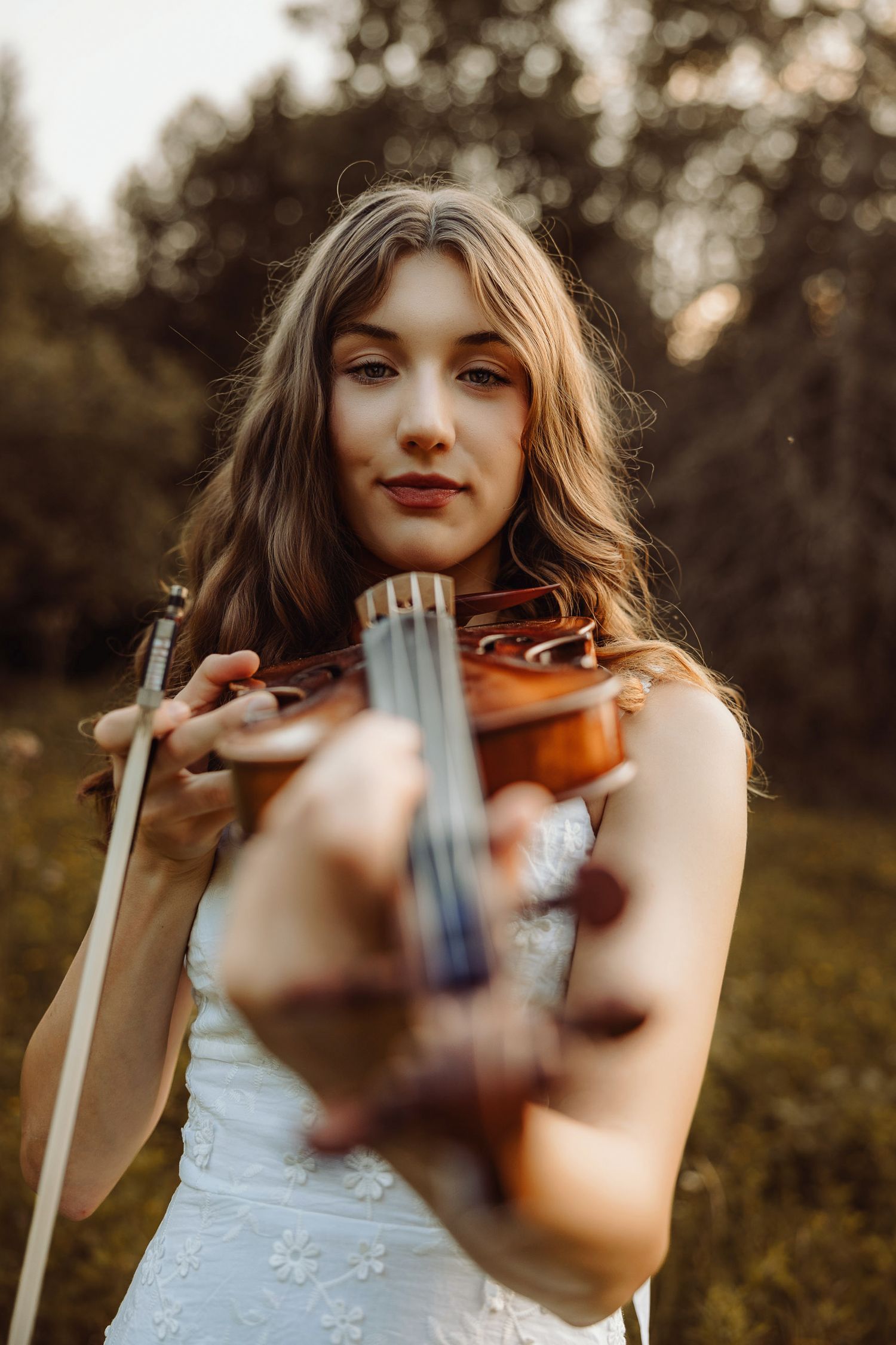 High school senior during golden hour with a violin in a field in Marquette, Michigan.