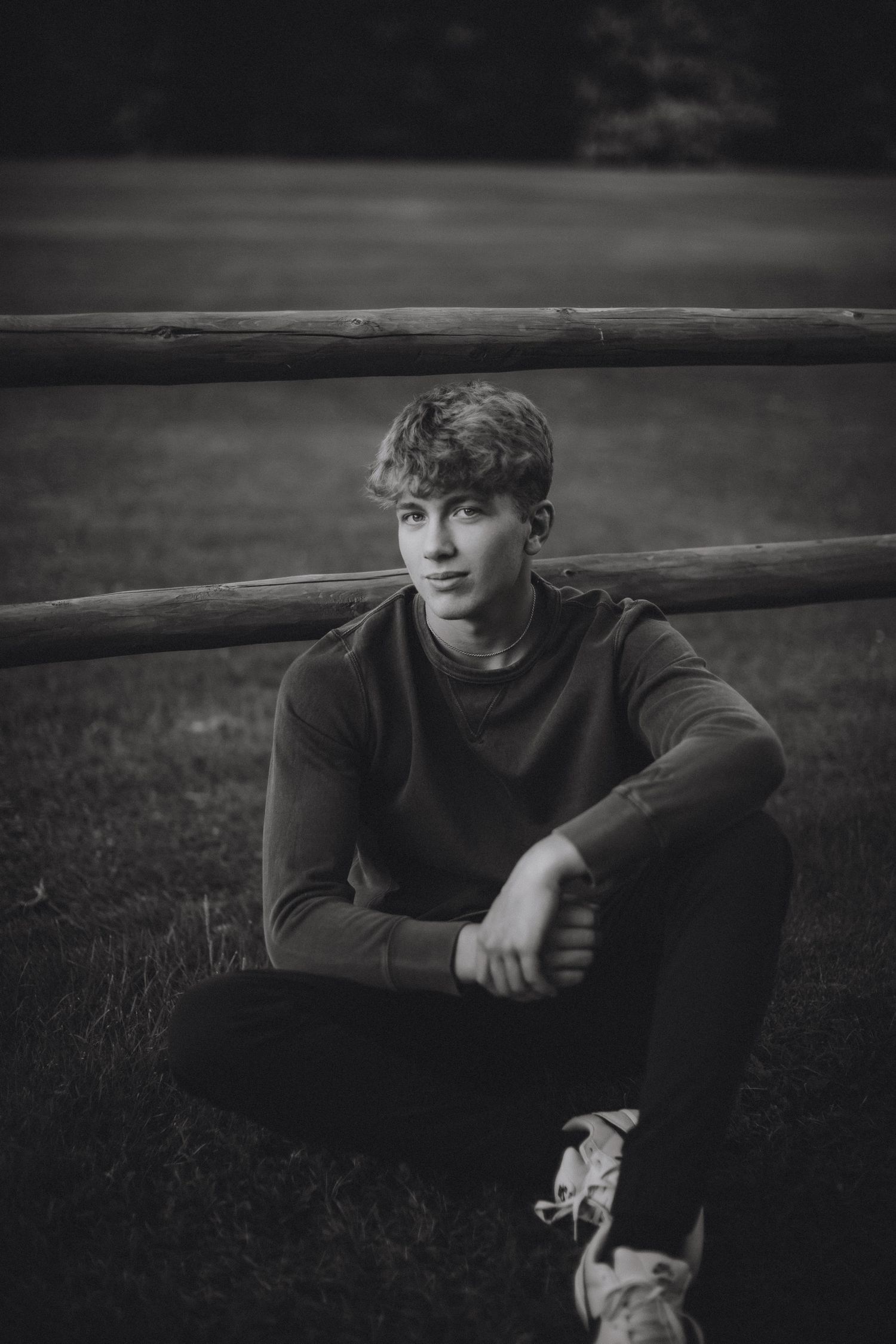 high school senior guy boy portraits sitting on ground by fence. Escanaba, Marquette, NYC senior portrait photographer