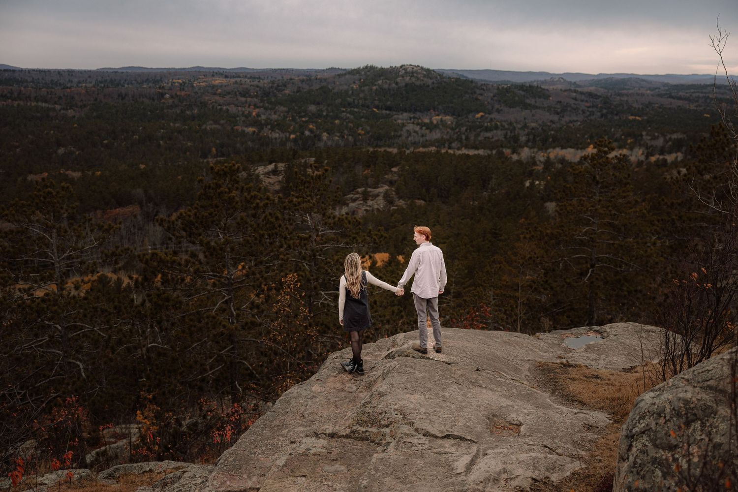 Engagement picture on top of a mountain, couple holding hands, laughing, sugar loaf Marquette, Michigan.