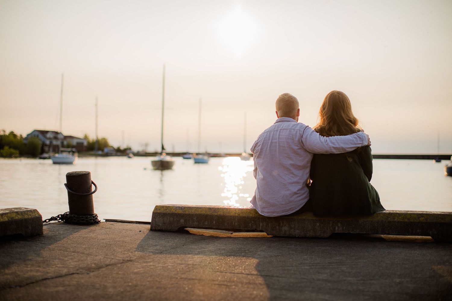 Sunrise engagement pictures downtown Marquette, Michigan. on the Lake Superior shore with sail boats.