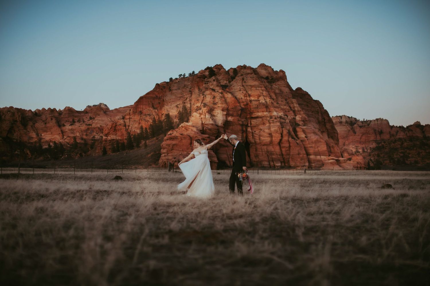 Bride and groom dance at sunset at a desert near Zion National Park in Utah.